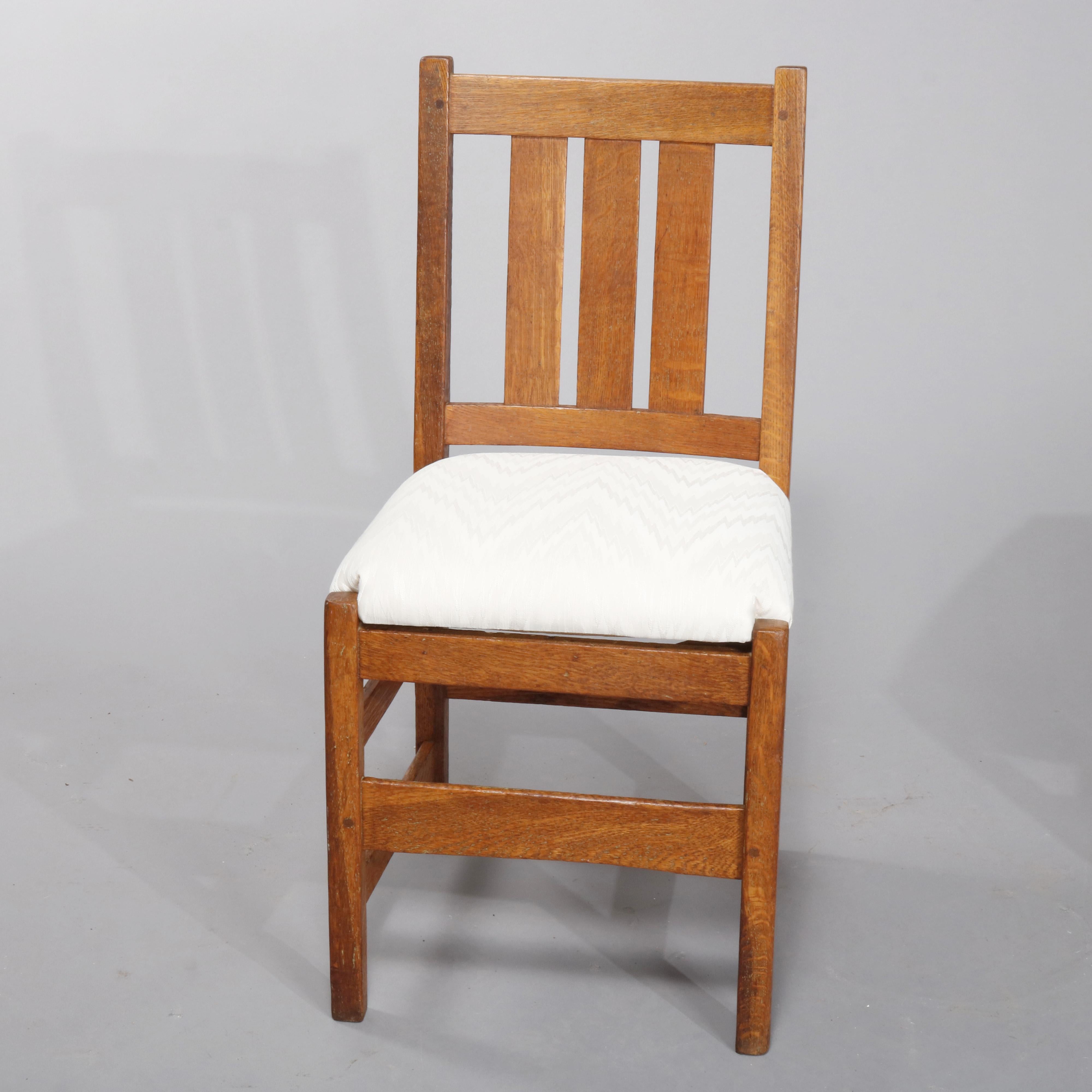 A set of four antique Arts & Crafts Mission dining chairs by L. & J.G. Stickley offers quarter sawn oak construction with slat backs over upholstered seats, raised on straight and square legs, circa 1910

Measures: 35.25