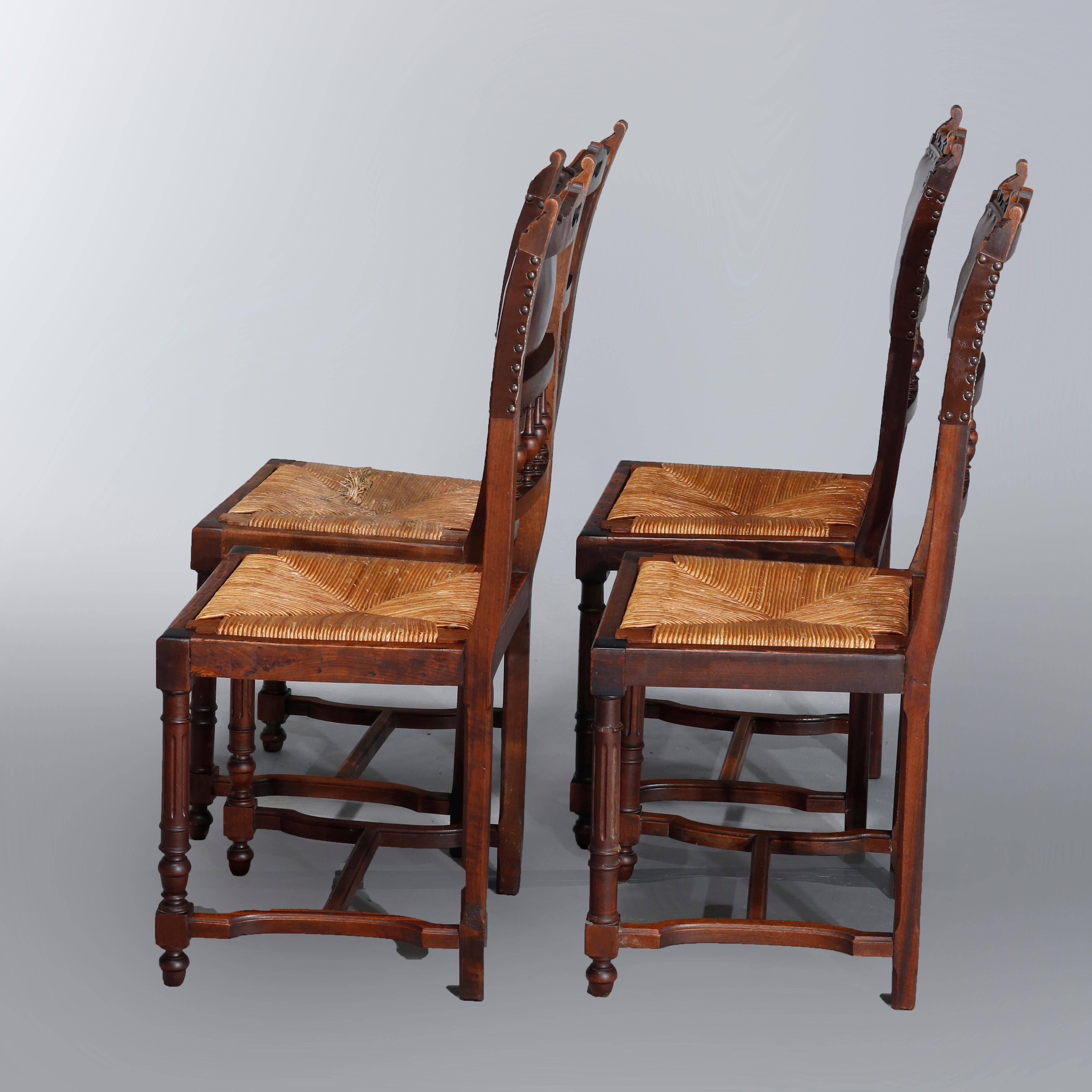 Set of four antique French Renaissance dining chairs each with pierced scroll and foliate crest over leather back and spindle rail with flanking acanthus finials and over rush seat, raised on reeded legs with Marseille bun feet, 19th