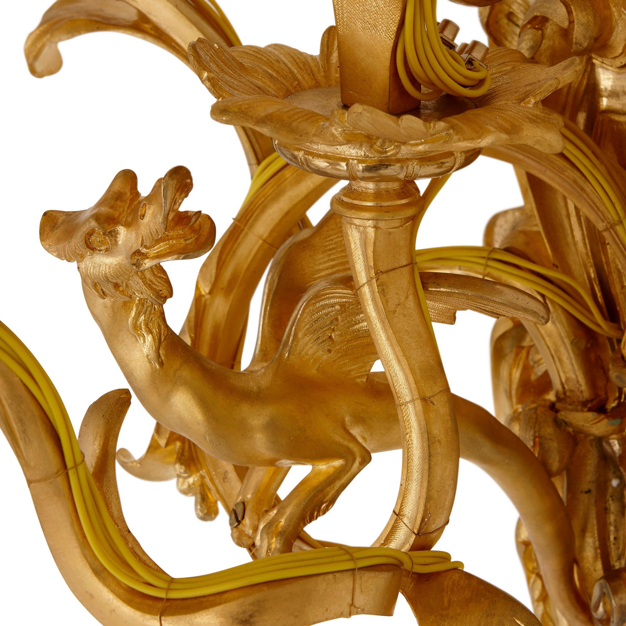 Diese Wandleuchter aus vergoldeter Bronze (Ormolu) sind kunstvoll und sehr elegant gestaltet. Sie sind im Rokoko-Stil gehalten, nach dem Vorbild der dekorativen Kunst der Zeit Ludwigs XV. in Frankreich (1715-1774). 

Die Wandleuchter sind im