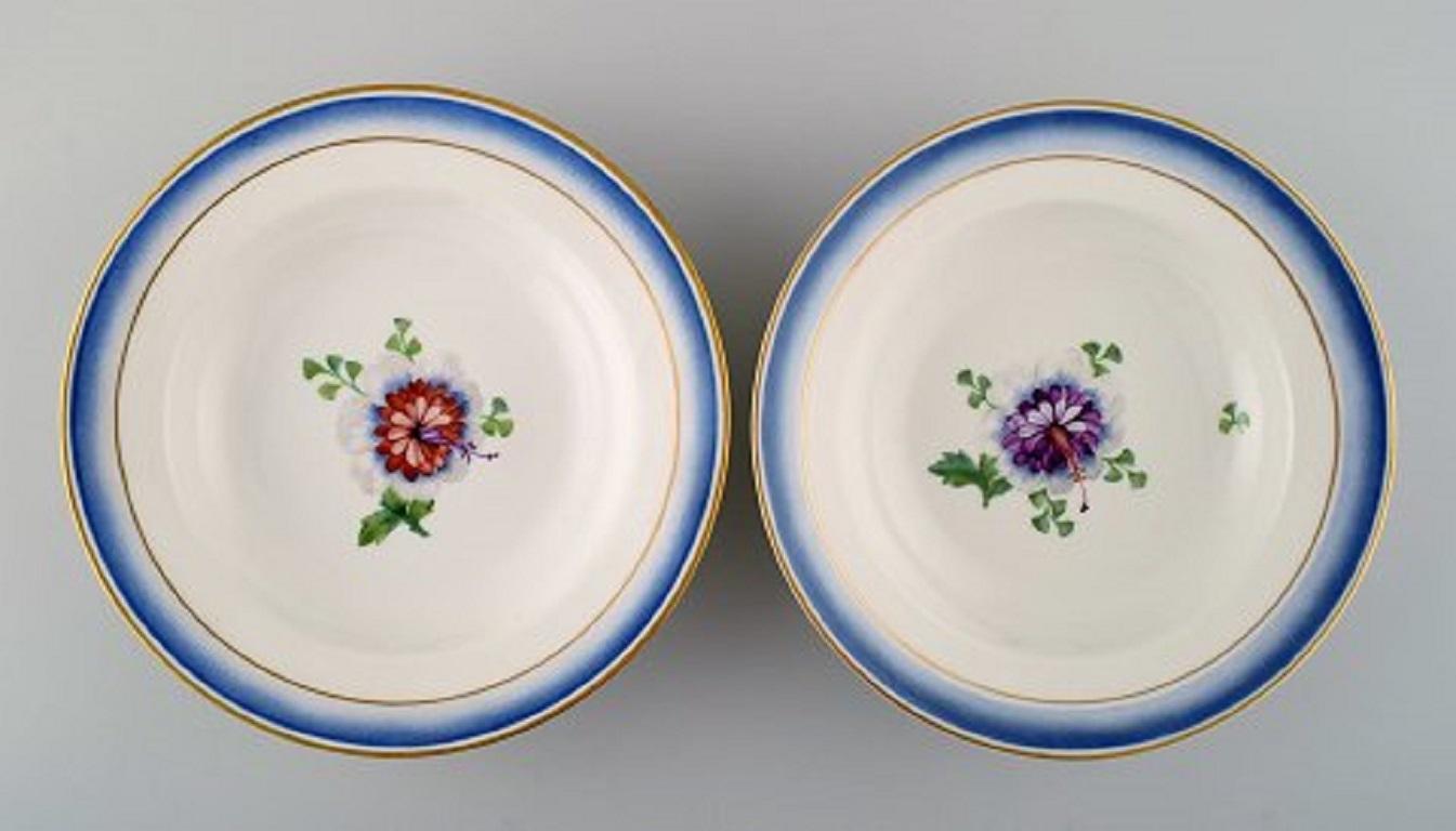 Quatre assiettes profondes anciennes Royal Copenhagen en porcelaine peinte à la main avec des fleurs et un bord bleu avec de l'or. Modèle numéro 592/9050, fin du 19ème siècle.
Mesures : 21 x 4 cm.
1ère qualité d'usine.
En très bon