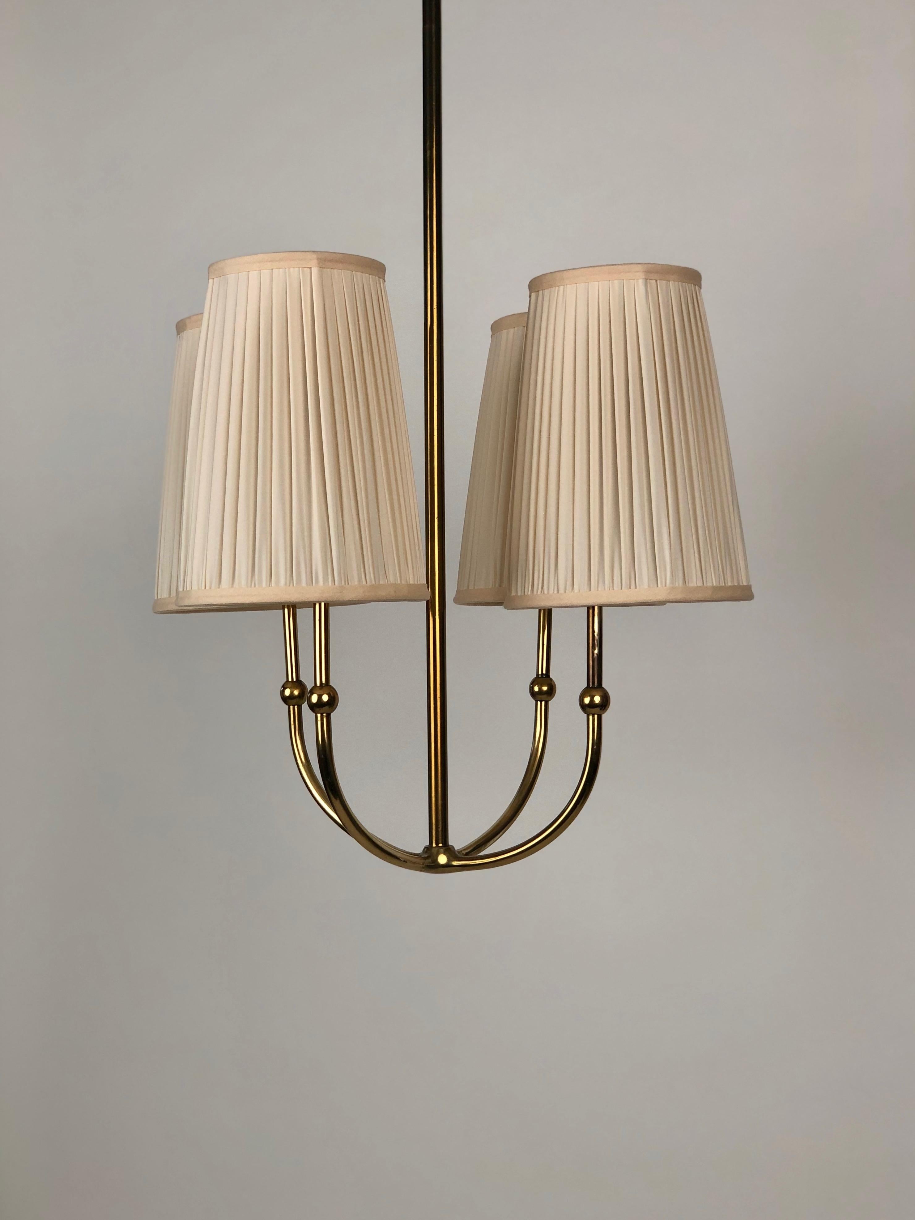 This is a beautifully proportioned brass chandelier from the 1930's, with a poetic form . 
I find it simply: Wow.
The relationship of the various elements and their proportions make it sing in the right environment .
The shades have been revitalised