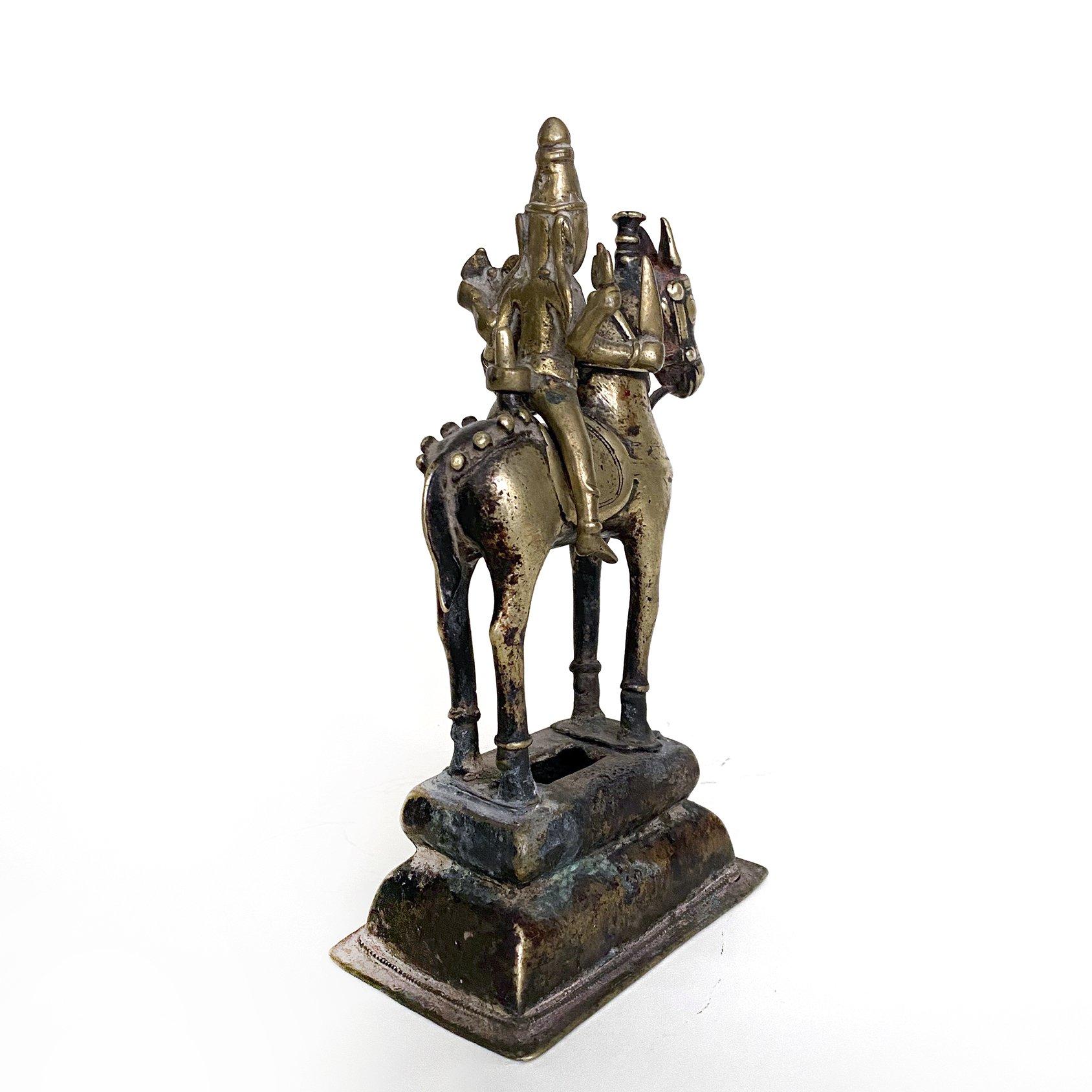 Four armed Shiva on horse holding Uma, brass bronze, India, 19th century.
The God Shiva with four arms astride on a horse, one arm holding Uma, his wife and on the upper right hand holding a trident. Mounted on a brass pedestal, the figure of Shiva