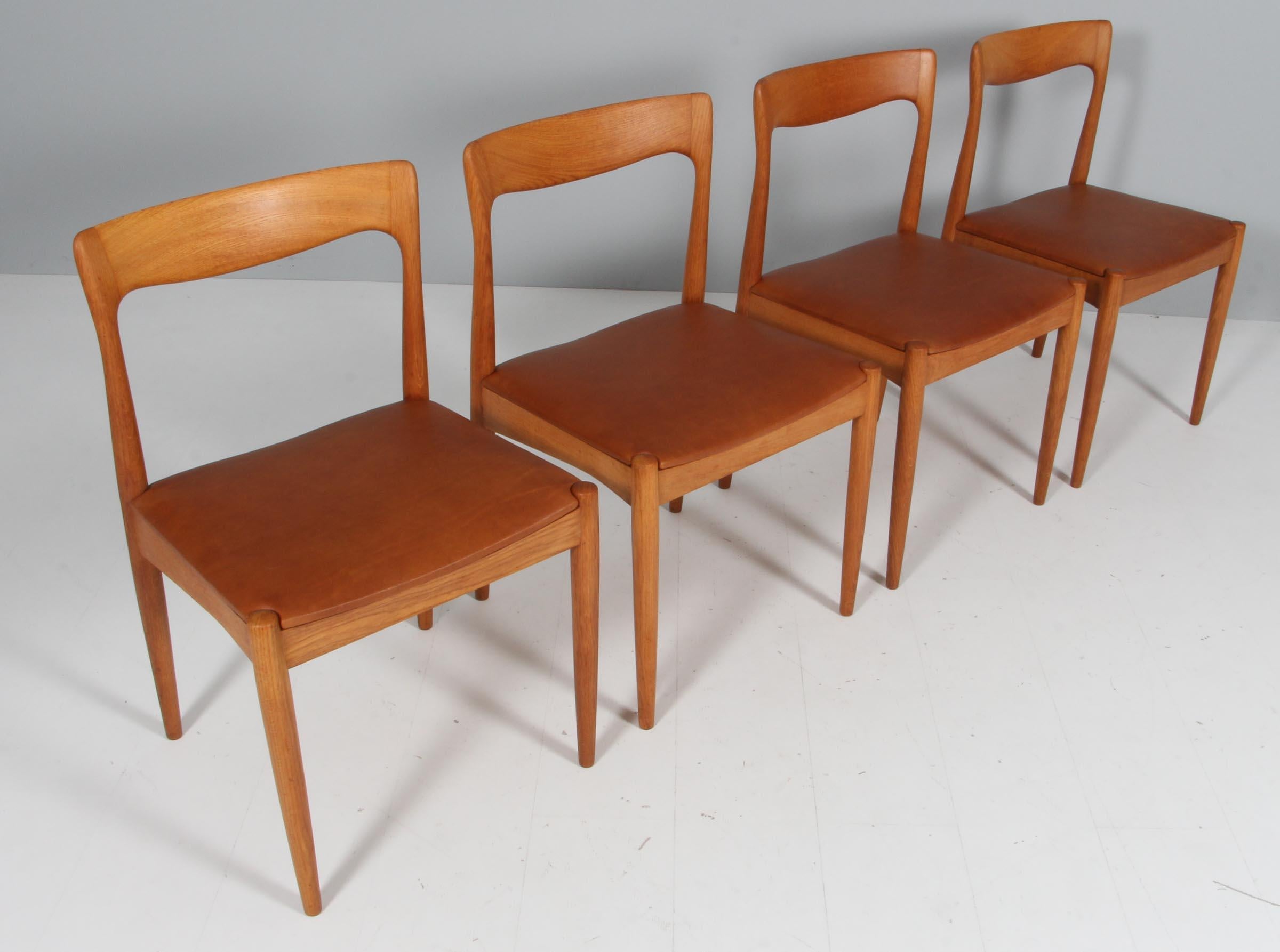 Set of four Arne Vodder dining chairs in solid oak.

New upholstered seats with tan aniline leather.

Made by Vamo.
