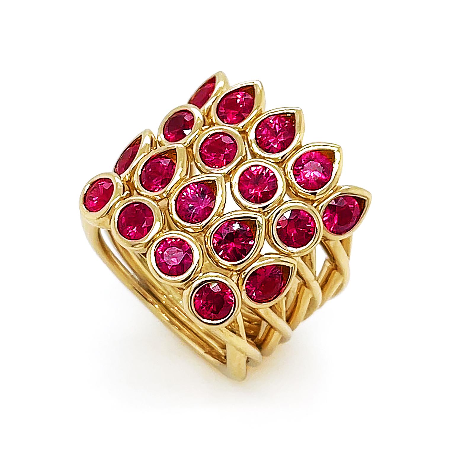 Majestic rubies flicker exceptional red and pink undertones. 18k yellow gold bezel settings secure alternating rows of pear and round cuts of the jewel. The illusion of stacked rings is created by each row having its own band, melded together. The