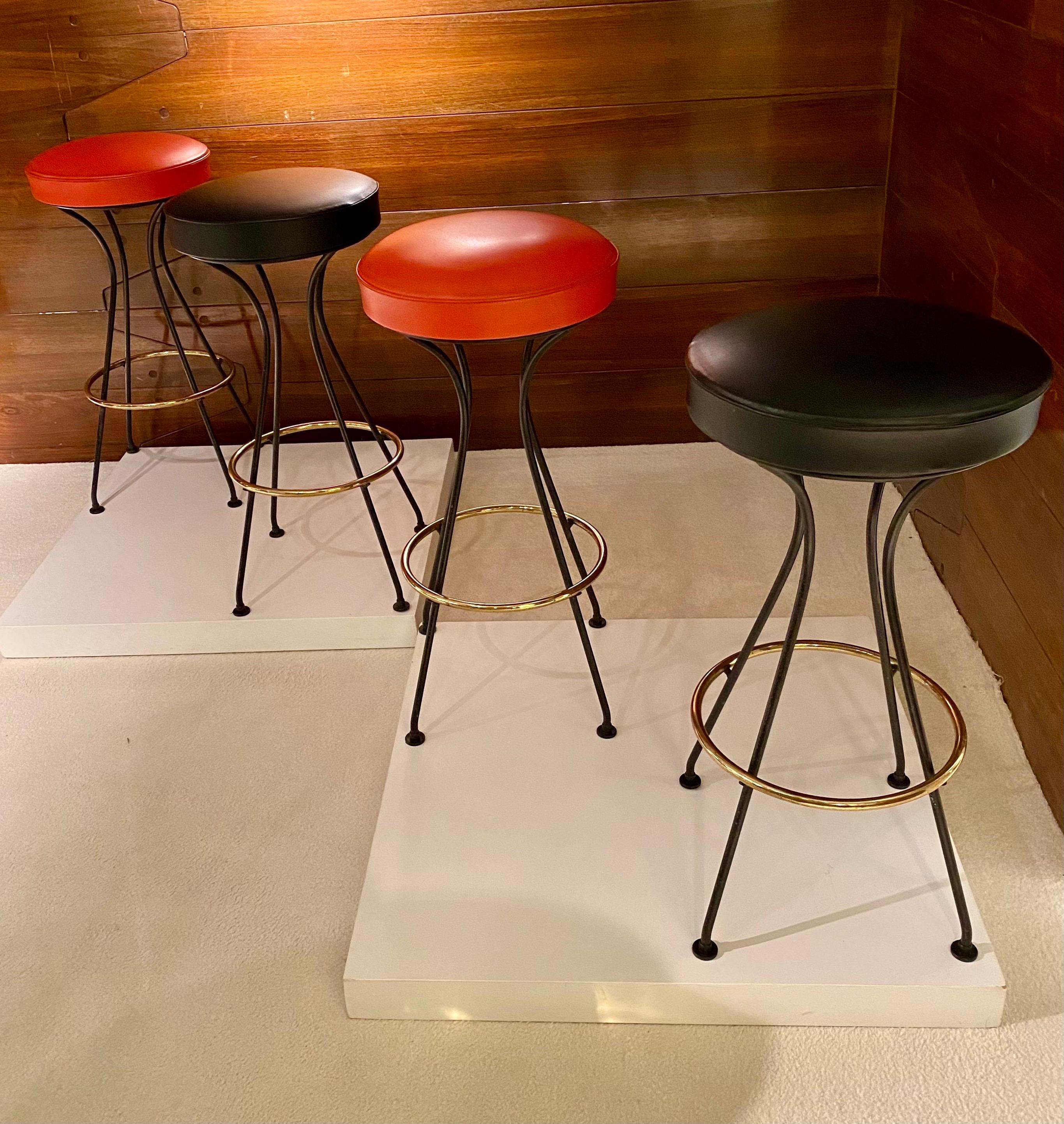 Quatre tabourets de bar, France années 1950.
Tabouret en métal laqué noir et laiton, siège orange et noir en simili cuir original.