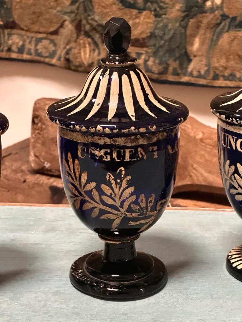Four fine 18th Century Italian apothecary jars, with painted design and lids, having a faceted knob.  9.75” h. x 5.25” diam with slight variations