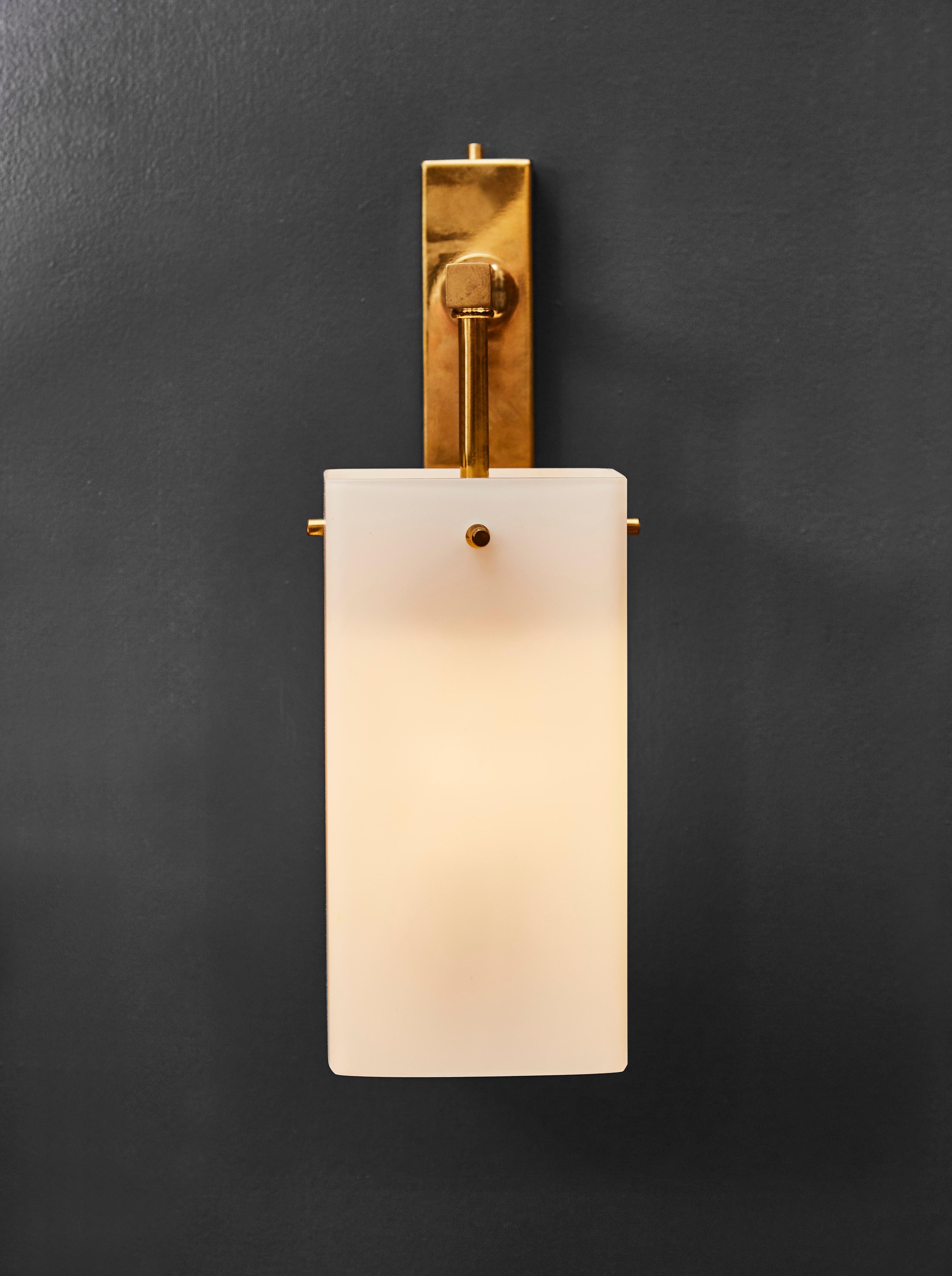 Set of four chic wall sconces made of brass supporting rectangular white glass shades.