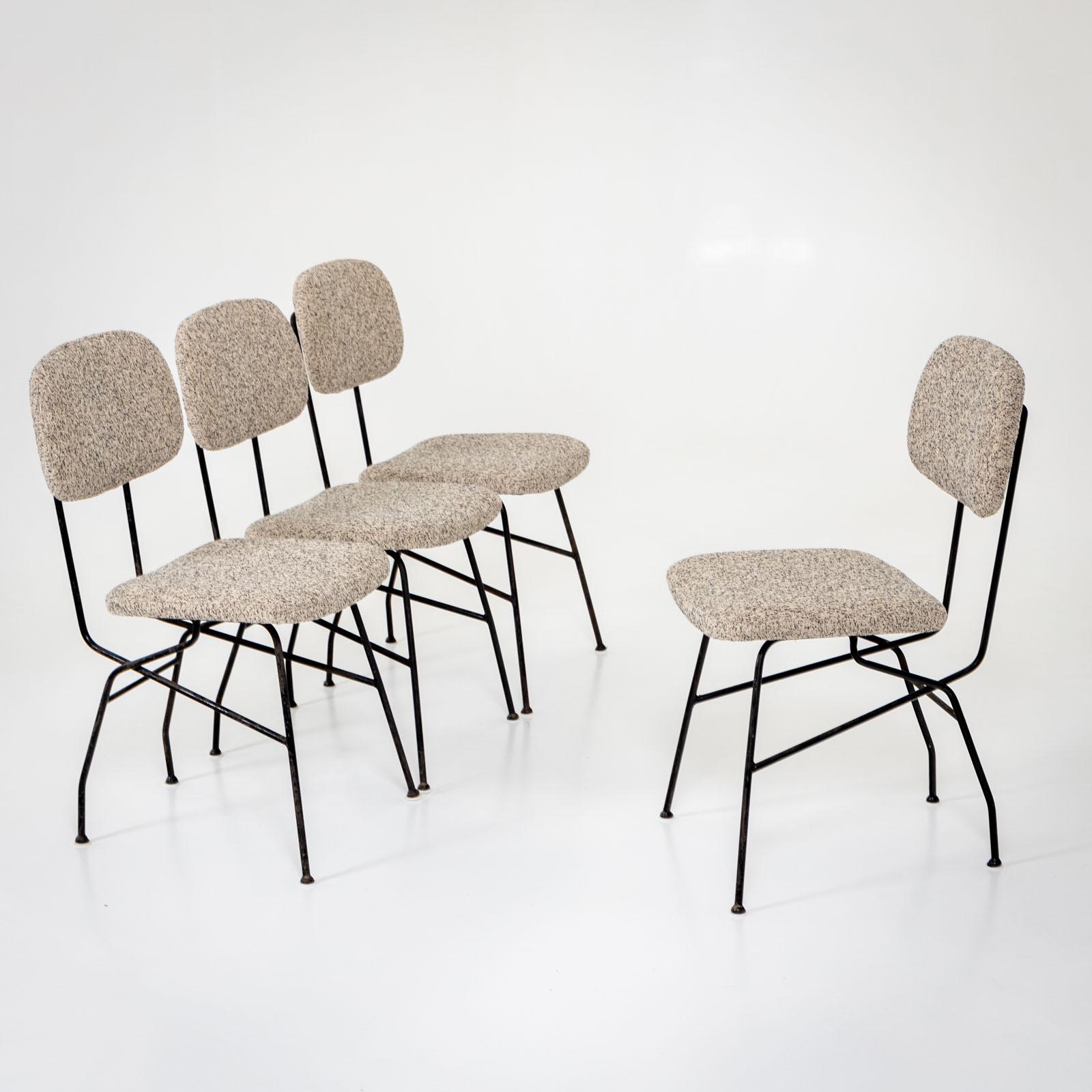 Ensemble de quatre chaises Cocorita sur des châssis en fer noir. Les chaises sont dotées d'un dossier et d'une assise rembourrés et ont été nouvellement revêtues d'un tissu chiné noir et blanc. 