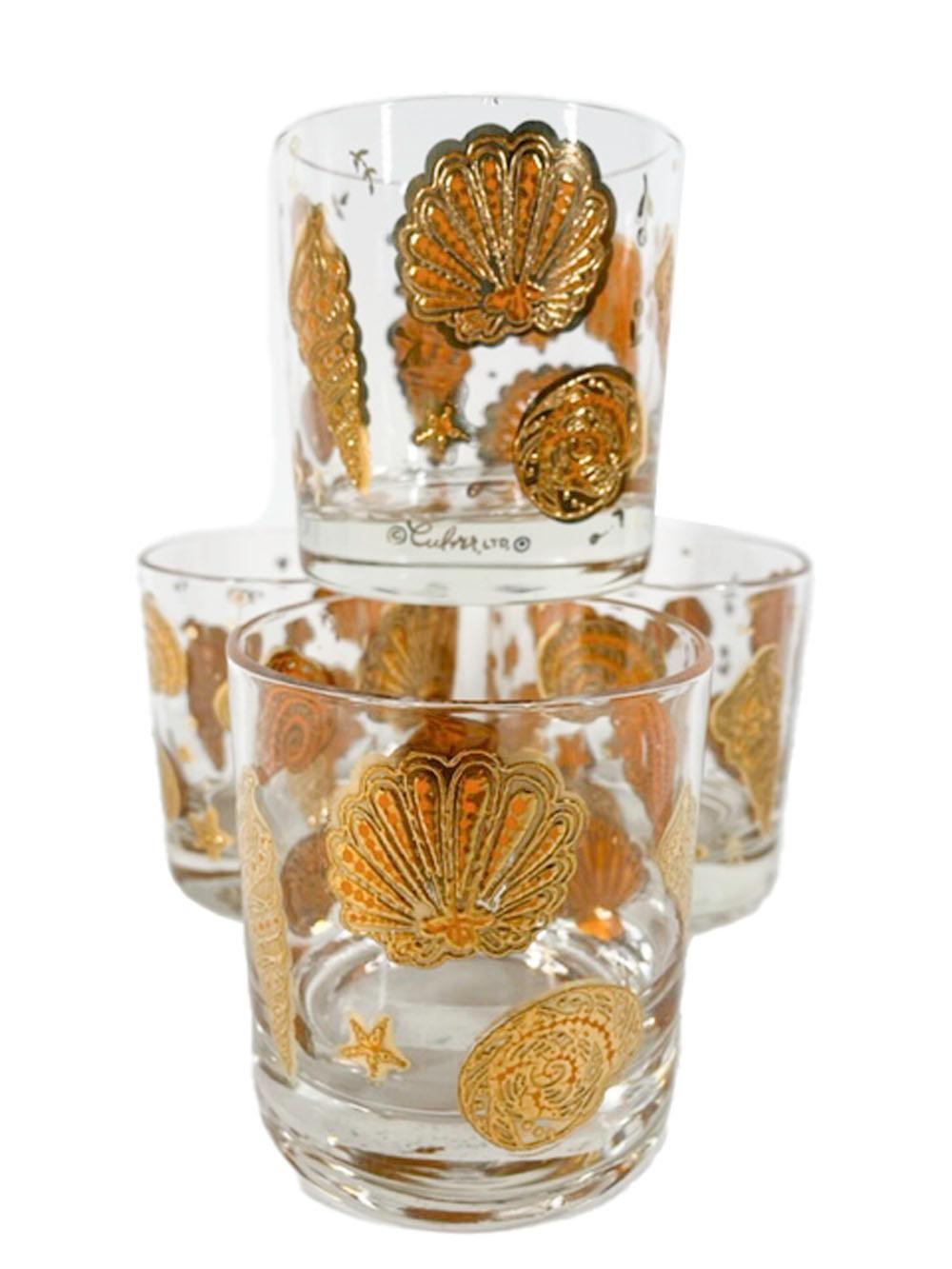 Four Mid-Century Modern rocks glasses in Marina pattern by Culver, having various seashells in heaped orange enamel and 22 karat gold creating a raised textured design.
