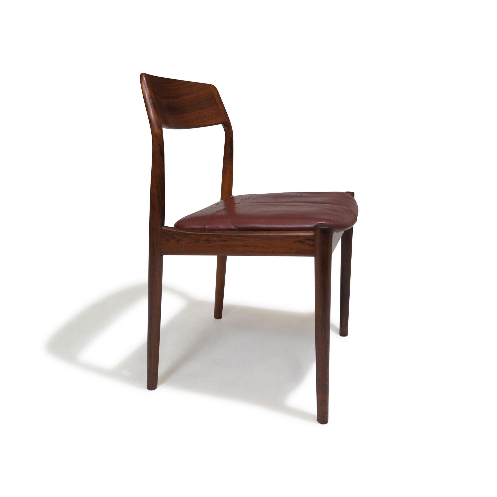 Set of 4 Mid-Century rosewood dining chairs, 1958, Denmark. Handcrafted from solid Brazilian rosewood, the frames feature comfortable angled backrests and are upholstered in patinated burgundy leather with a patchwork pattern. The chair frames have