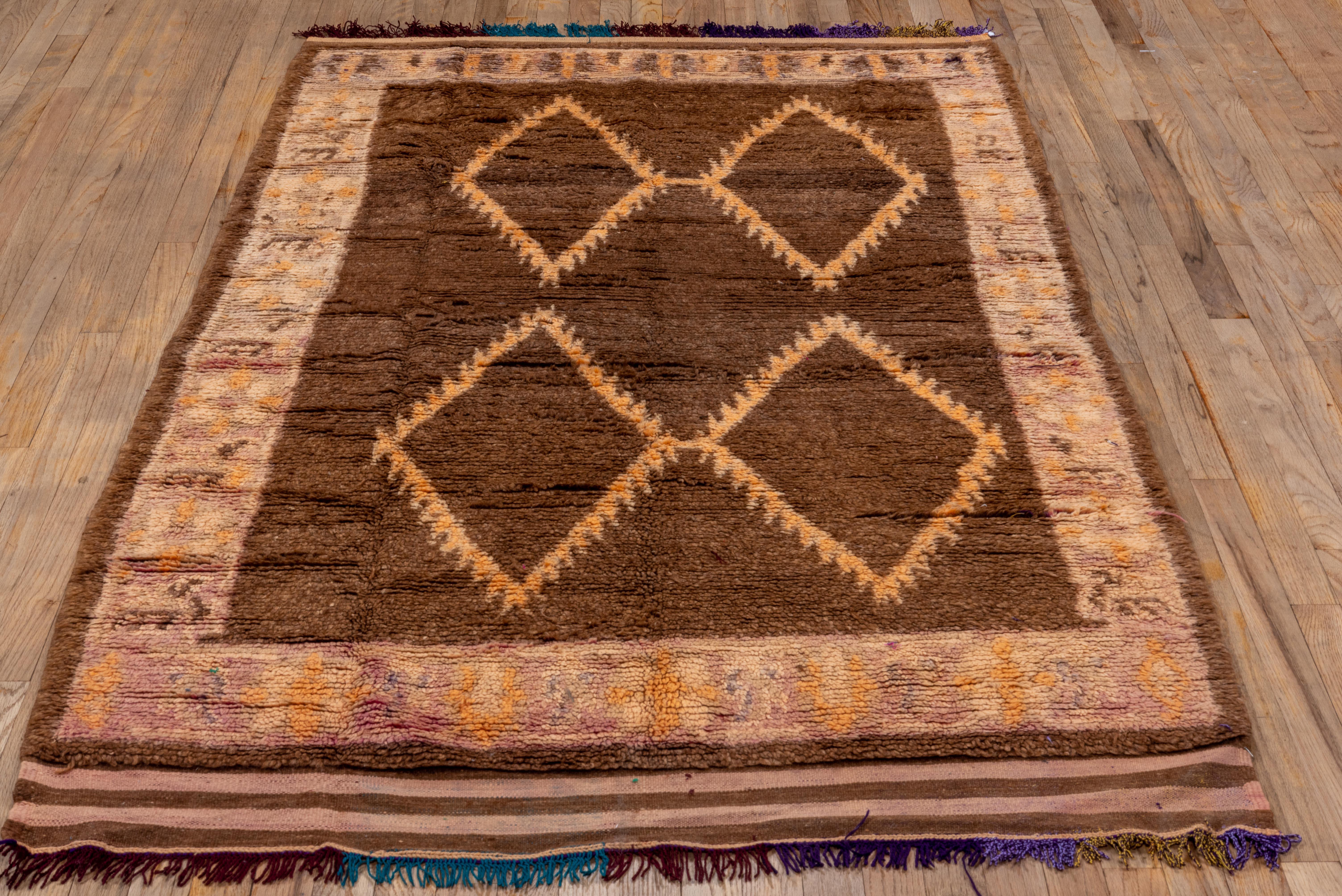 100% wool antique Moroccan rug with four bold diamonds making up the center field, color is brown gold and purple with a detailed inner border and tassels on both length sides  