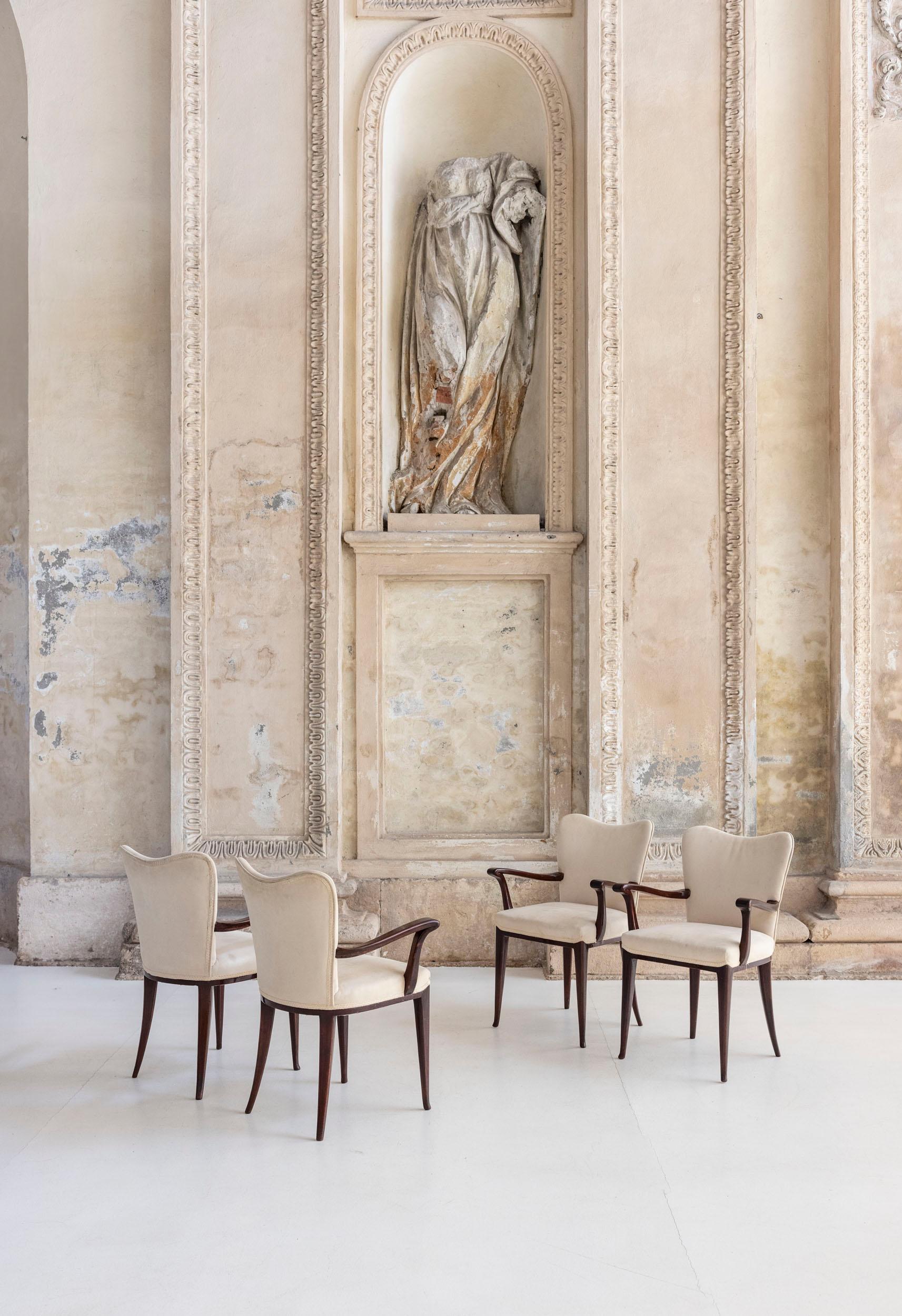 Set of four elegant dining chairs by Osvaldo Borsani for Arredamenti Borsani. Crafted from dark wood, they feature soft, white upholstered seats and backs. The design is refined, with curved armrests that add a touch of fluid elegance.
They can