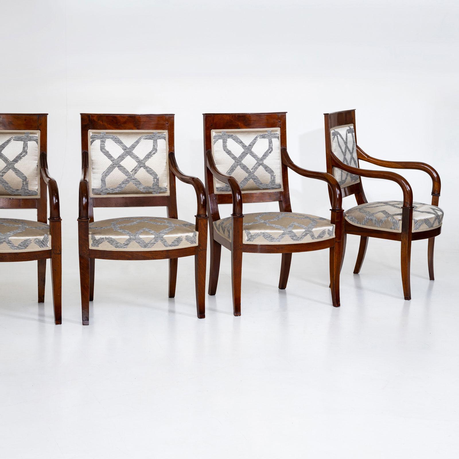 Four French armchairs made of solid mahogany with elegantly curved legs and a slightly rounded upholstered seat. The armrests slope down in a gentle curve and end on the extended legs. The rectangular backrest is also upholstered. The chairs are