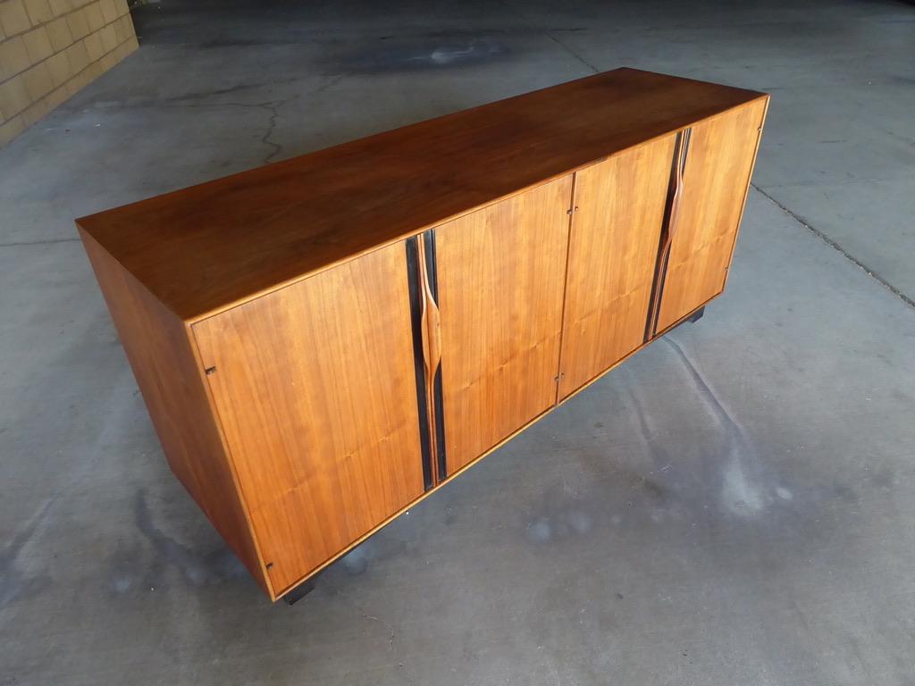 A four-door credenza/cabinet designed by John Kapel for Glenn of California in the 1960s. The cabinet is make of solid walnut, walnut vaneers and black laminate. Each door has a sculpted, integrated door pull and the base is ebonized.