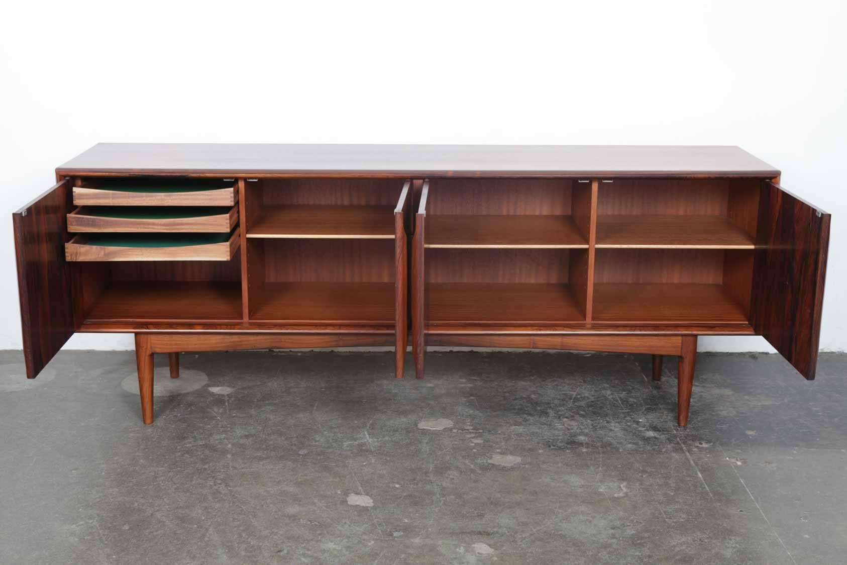Danish 1960s low rosewood four-door sideboard with incredible grain throughout, newly refinished in a satin lacquer. Interior storage includes three single shelf compartments and one compartment with three internal drawers. Each door has an elegant