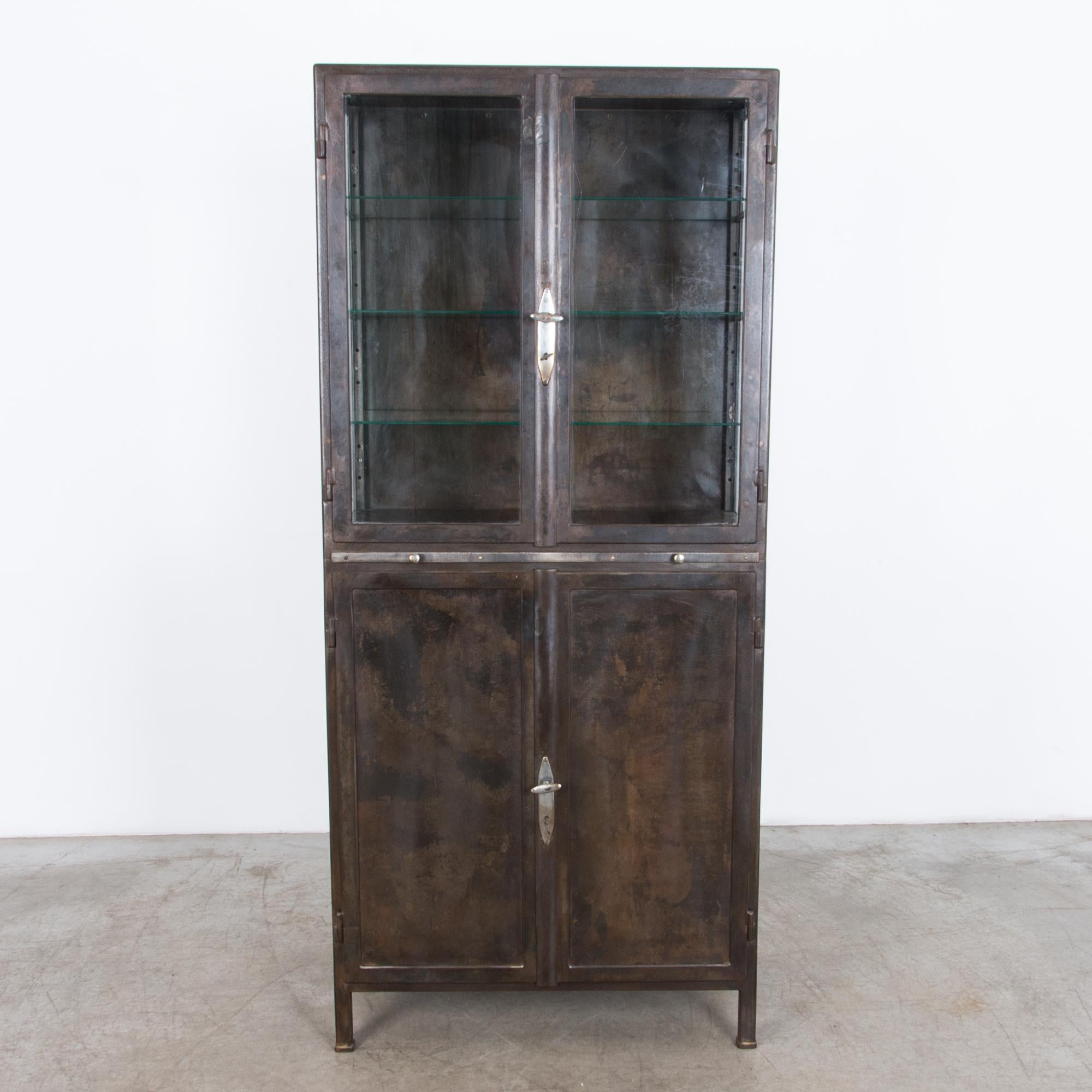A four door metal vitrine with pull-out shelf, from Czech Republic circa 1930. This polished steel cabinet was originally designed for industrial use, it features durable locking hardware and purpose built steel construction. The glass interior