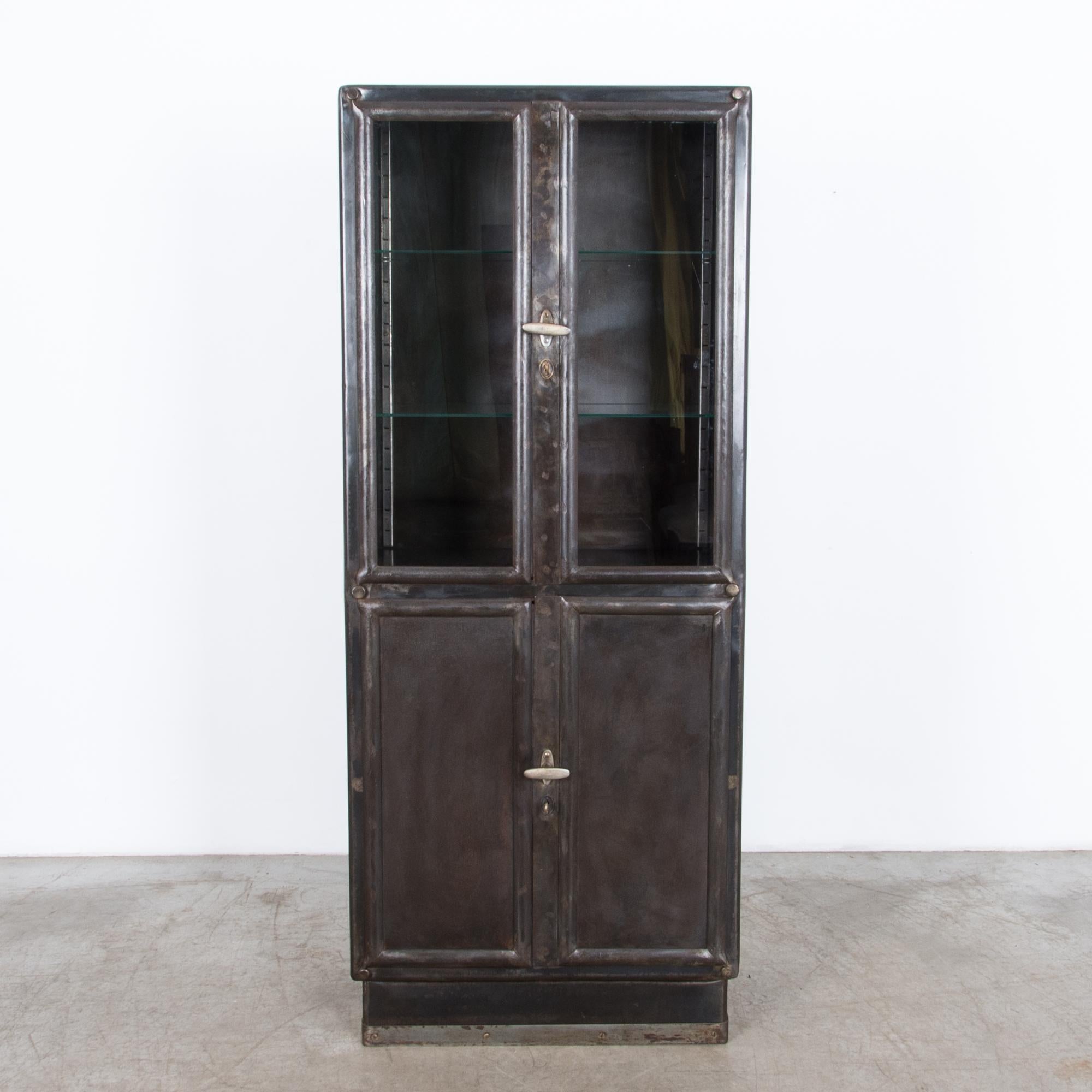 A four-door metal vitrine from Czech Republic, circa 1930. This polished steel cabinet was
originally designed for Industrial use, it features durable locking hardware and purpose built steel construction. The glass interior shelves, and textured