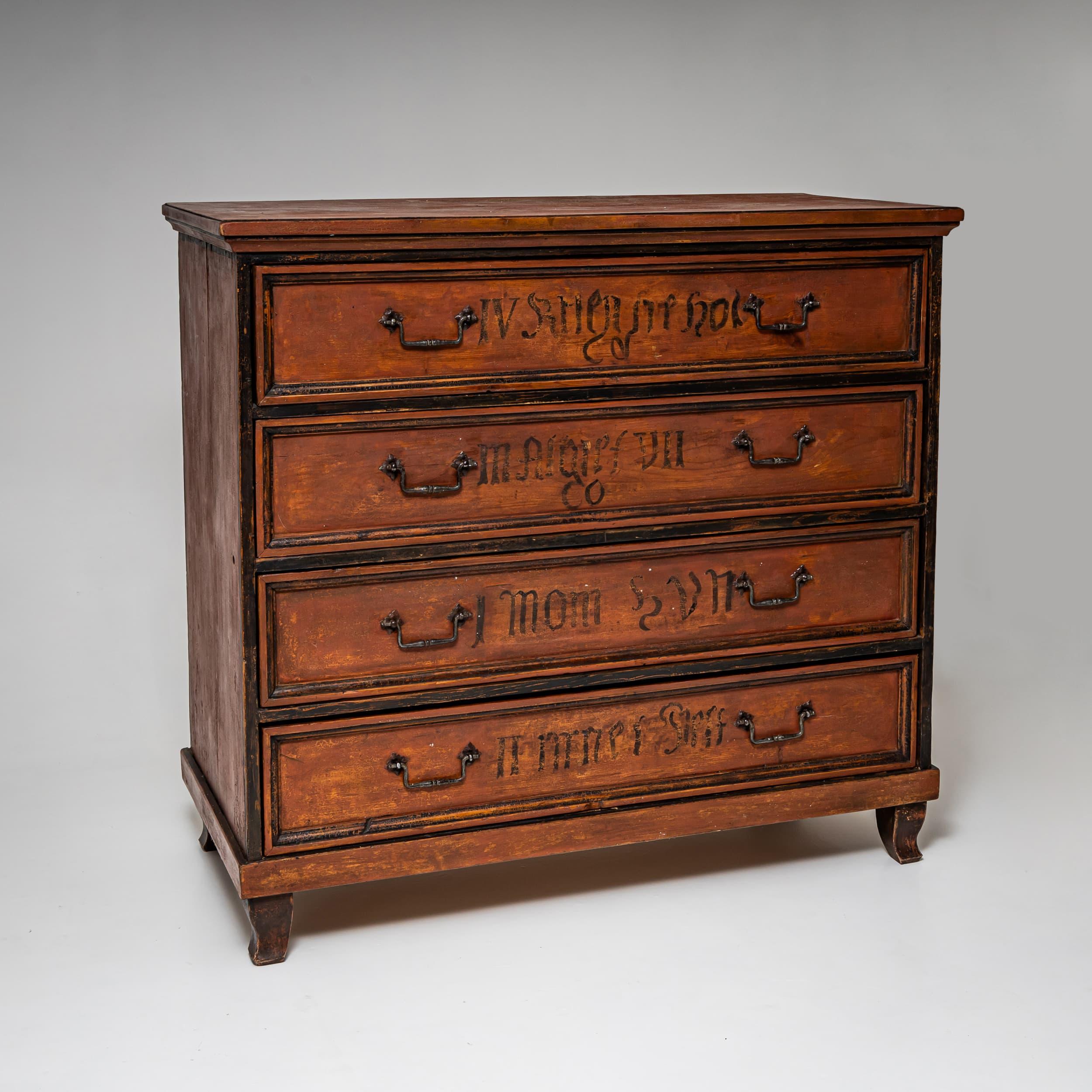 A German chest of drawers from the late 18th century. The piece features a straight-sided body with four drawers, resting on simple bracket feet. Its warm brown finish is accented with contrasting black frames around each drawer front. The chest