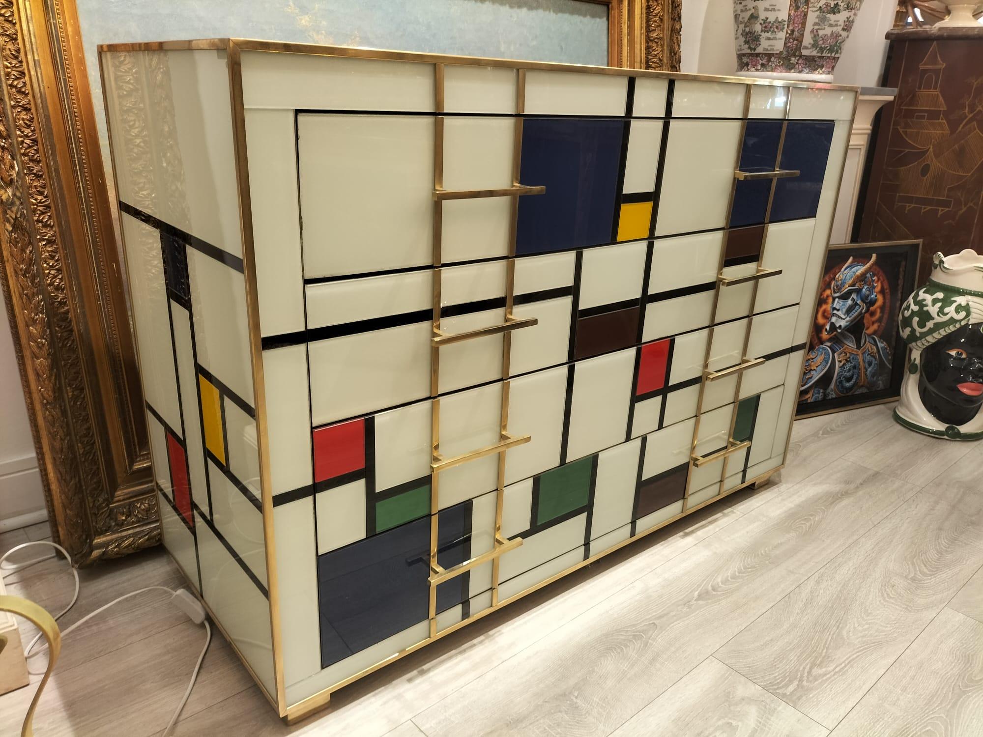 This commode features a striking design inspired by the geometric abstractions of Piet Mondrian, with a grid of black lines forming a pattern of rectangles and squares across its front surface. The shapes are filled with a mix of bright primary