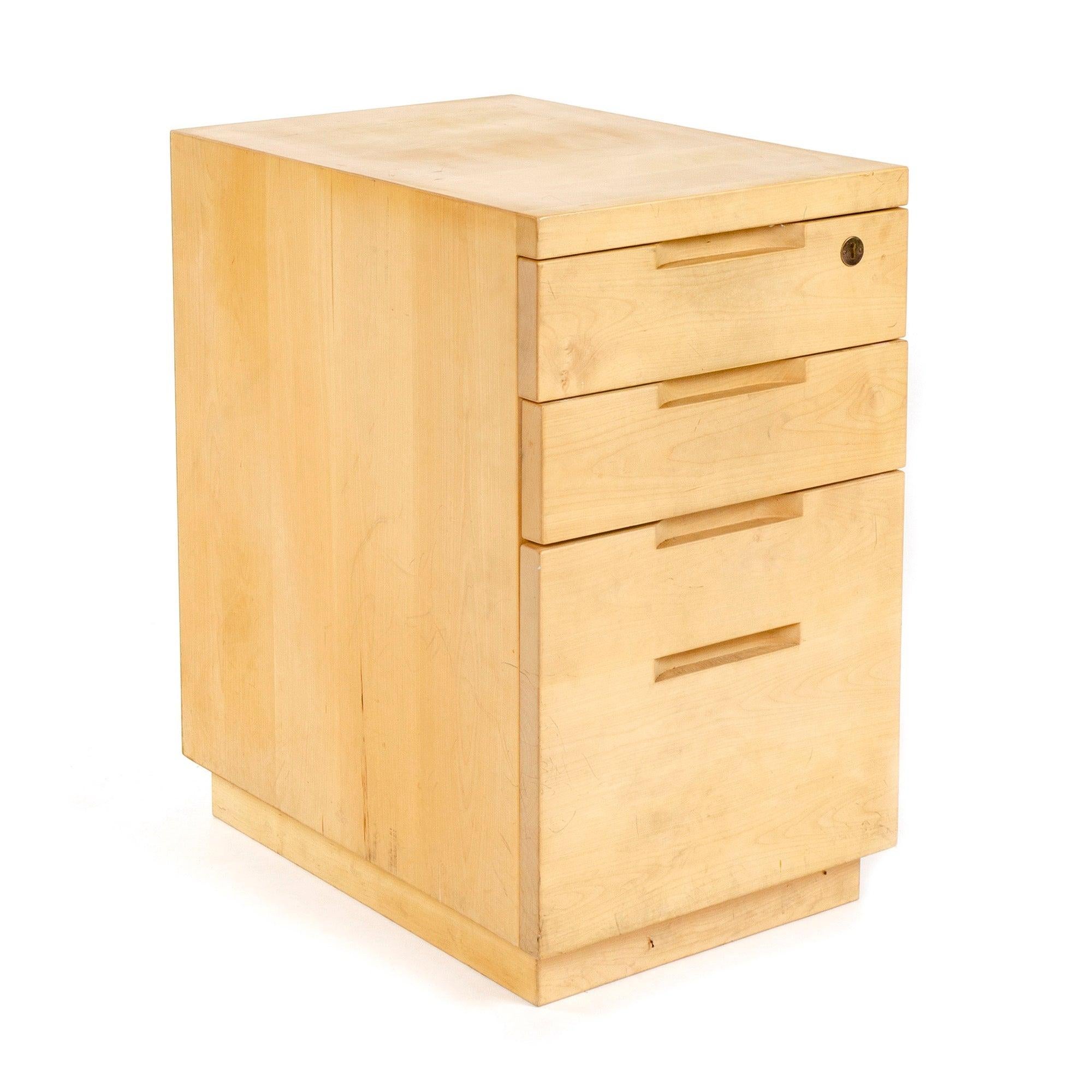 An office cabinet resting on a recessed plinth base, with four (4) drawers that lock and have integrated pulls.