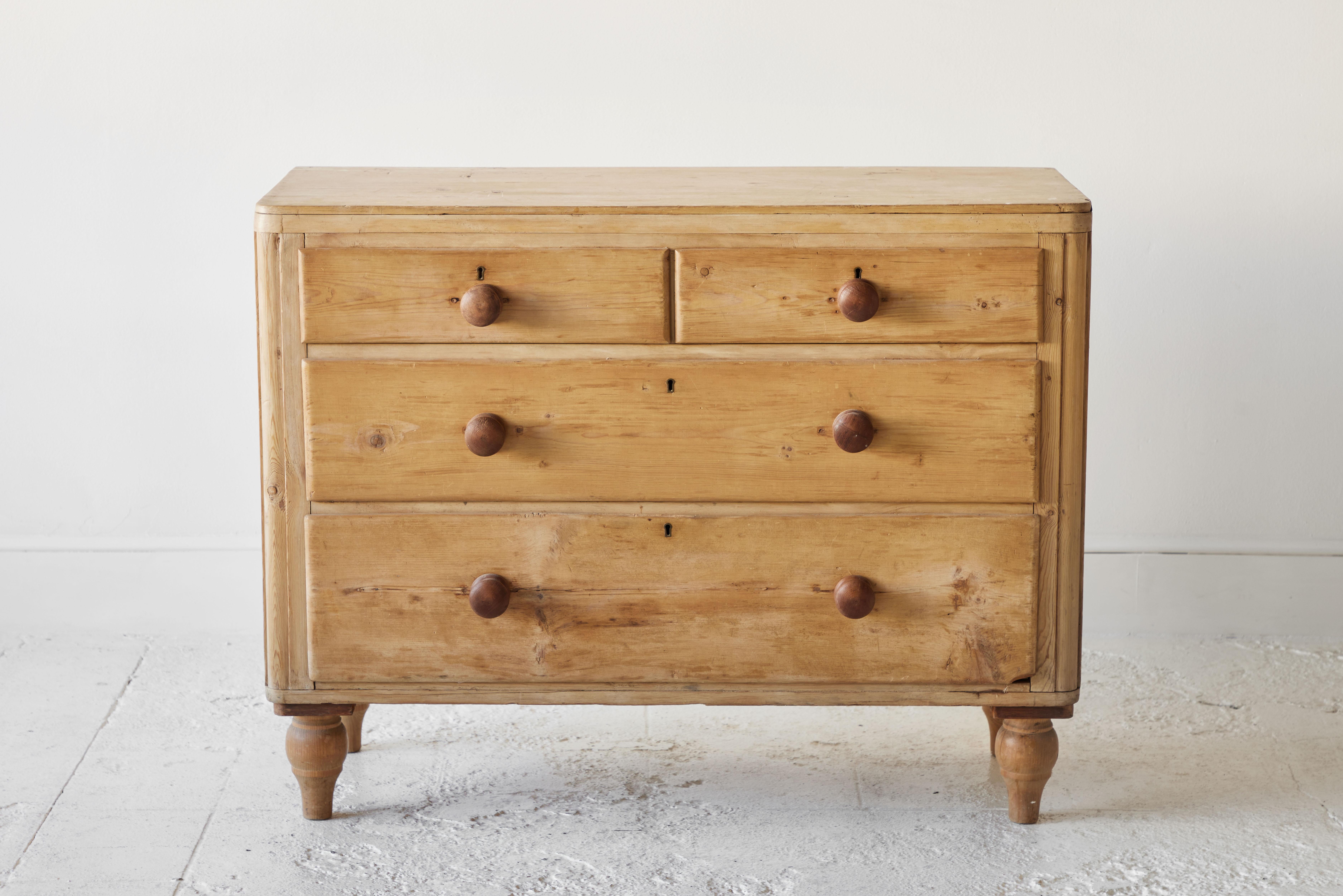 Four drawer pine chest of drawers sitting on four turned legs