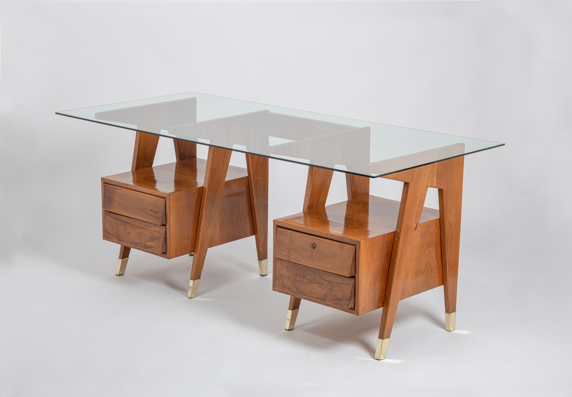 Ein wirklich eleganter Schreibtisch mit vier Schubladen aus Nussbaumholz und originaler Glasplatte, der dem Bologneser Architekten und Designer Melchiorre BEGA zugeschrieben wird. Dieser skulpturale Holzschreibtisch besticht durch seine schöne