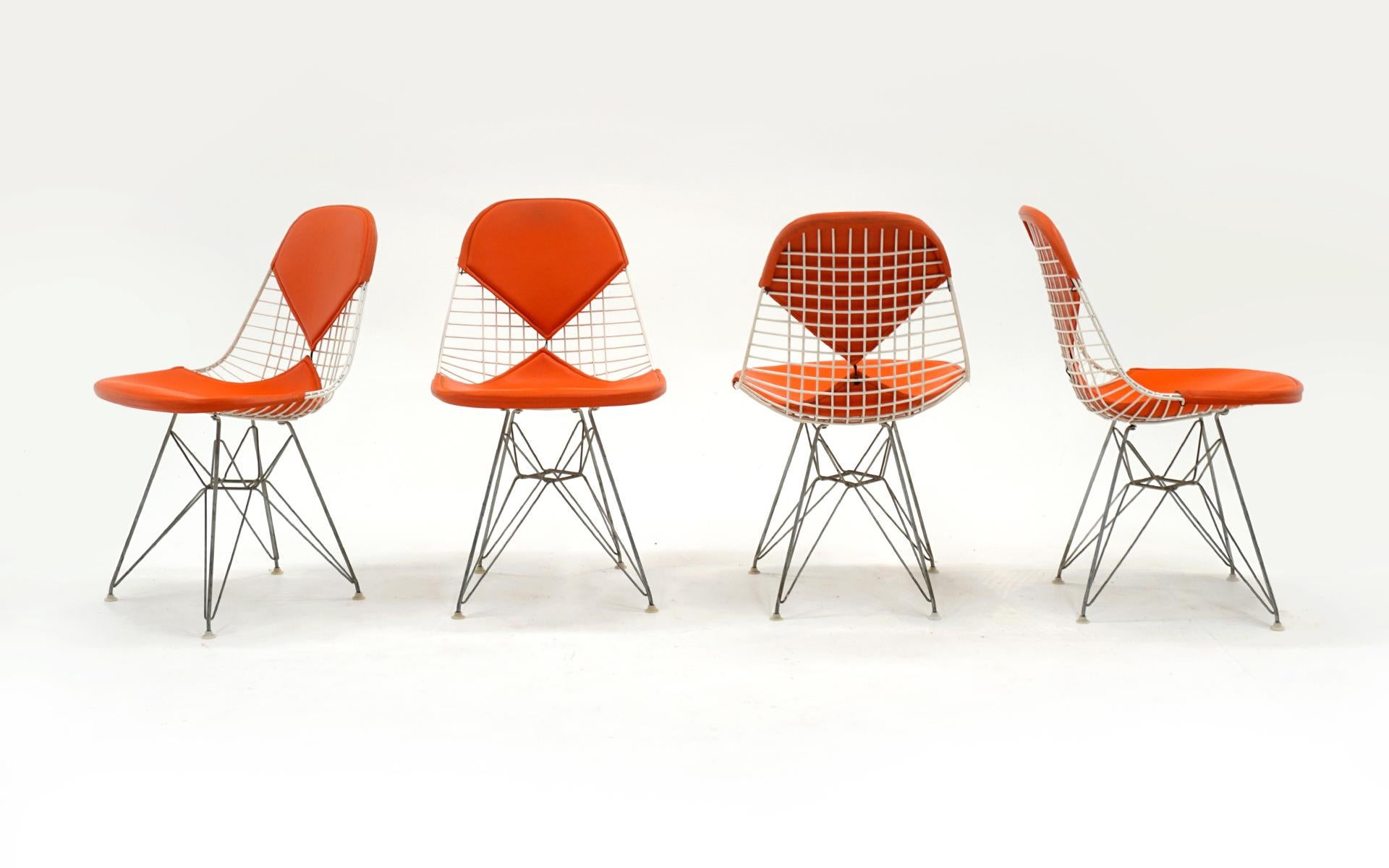 Set of four original white wire Charles and Ray Eames for Herman Miller white wire DKR dining chairs with original orange bikini covers. Zinc Eiffel Tower bases. All feet intact and original. Very good condition, ready to use.