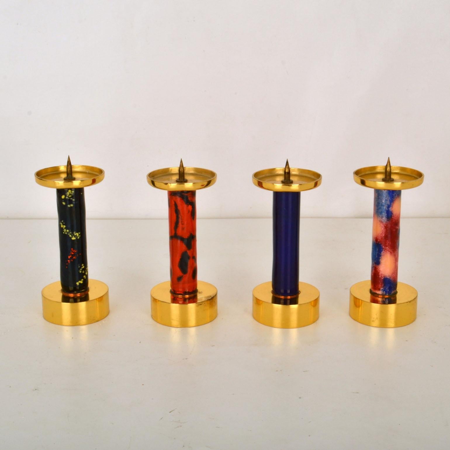 The simply formed gilded brass candlesticks are colorful decorated in enamels in red, black and blue. This age old traditional of enameling is taught and preserved by extremely skilled craftsmen. The process of vitreous enamels was developed by the