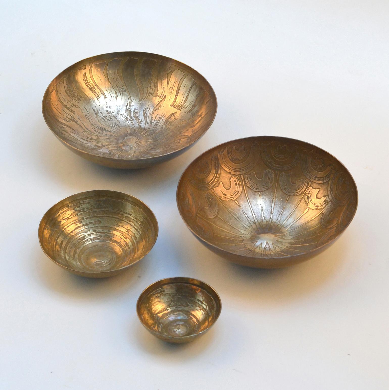 Four hand formed and etched decorative brass bowls designed by Michael Harjes and produced by Harjes Metallkunst, Bremen, West Germany, 1950's-60's. The etched technique of decoration is performed by hand painting strong acid which cuts into the