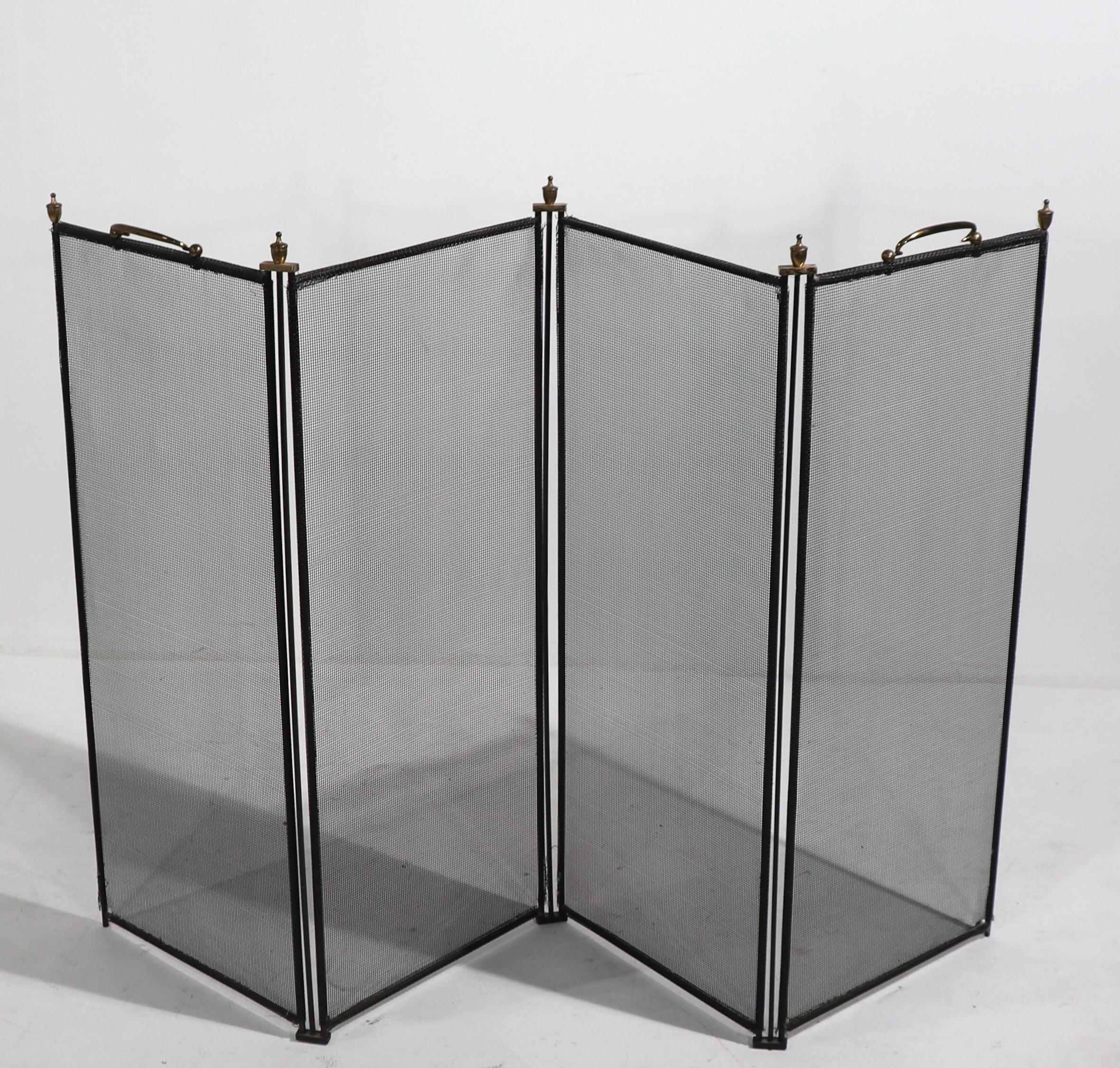 Nice tailored folding fireplace screen, having black screen and frame, with brass handles, and urn form finials. This example is in very good, original condition, showing only inconsequential fraying at the corners, please see images. 
Each panel