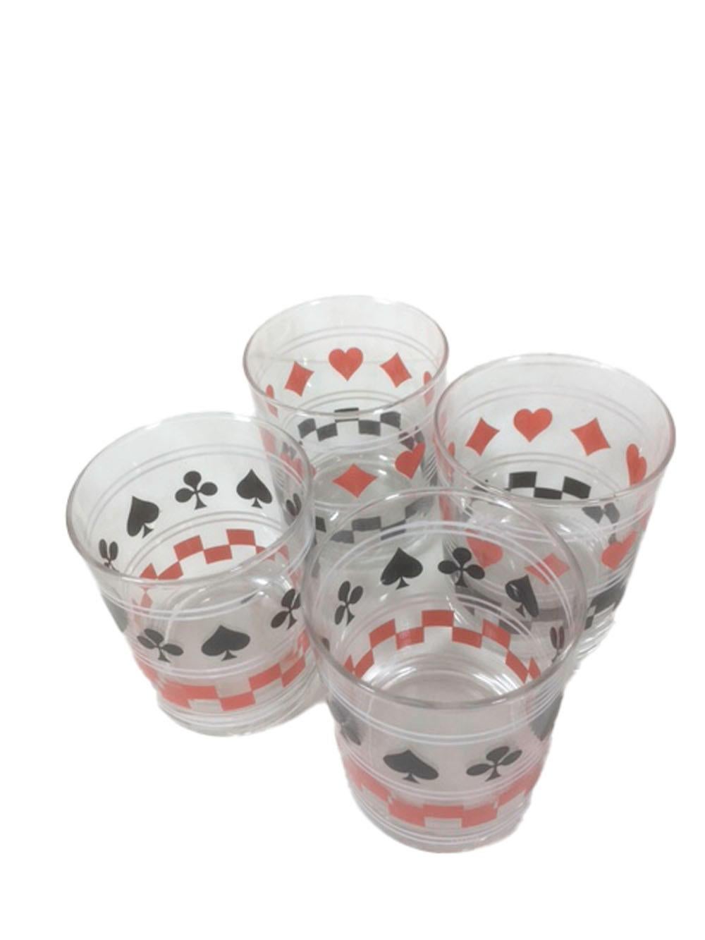 Art Deco set of 4 old fashioned or rocks glasses with a playing card motif. Two have spades and clubs alternating around the top half with a red check band around the bottom, while the other two have hearts and diamonds around the top with a black