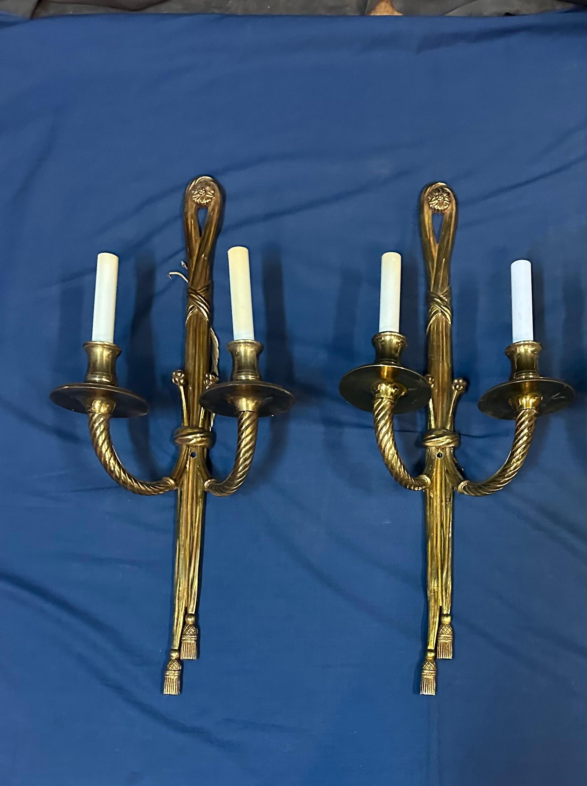 This vintage group of four matching French cast bronze wall sconces date from the early 1900’s. These sculpted sconces display a fashionable ribbon & tassel motif & an understated elegance that creates a proper accent for the right room setting. 