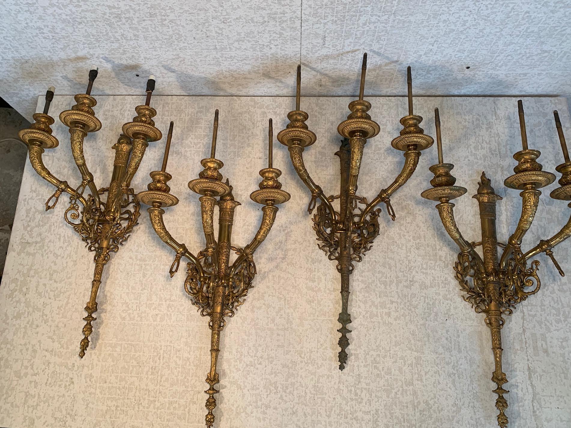 Two, exceptional pairs of 19th century 3-arm gas sconces featuring Horn-shaped arms ornamented with anthemions and terminating in urn form candle cups with swags. Sconce body depicts torchier wreathes with pierced olive branches and ribbons.