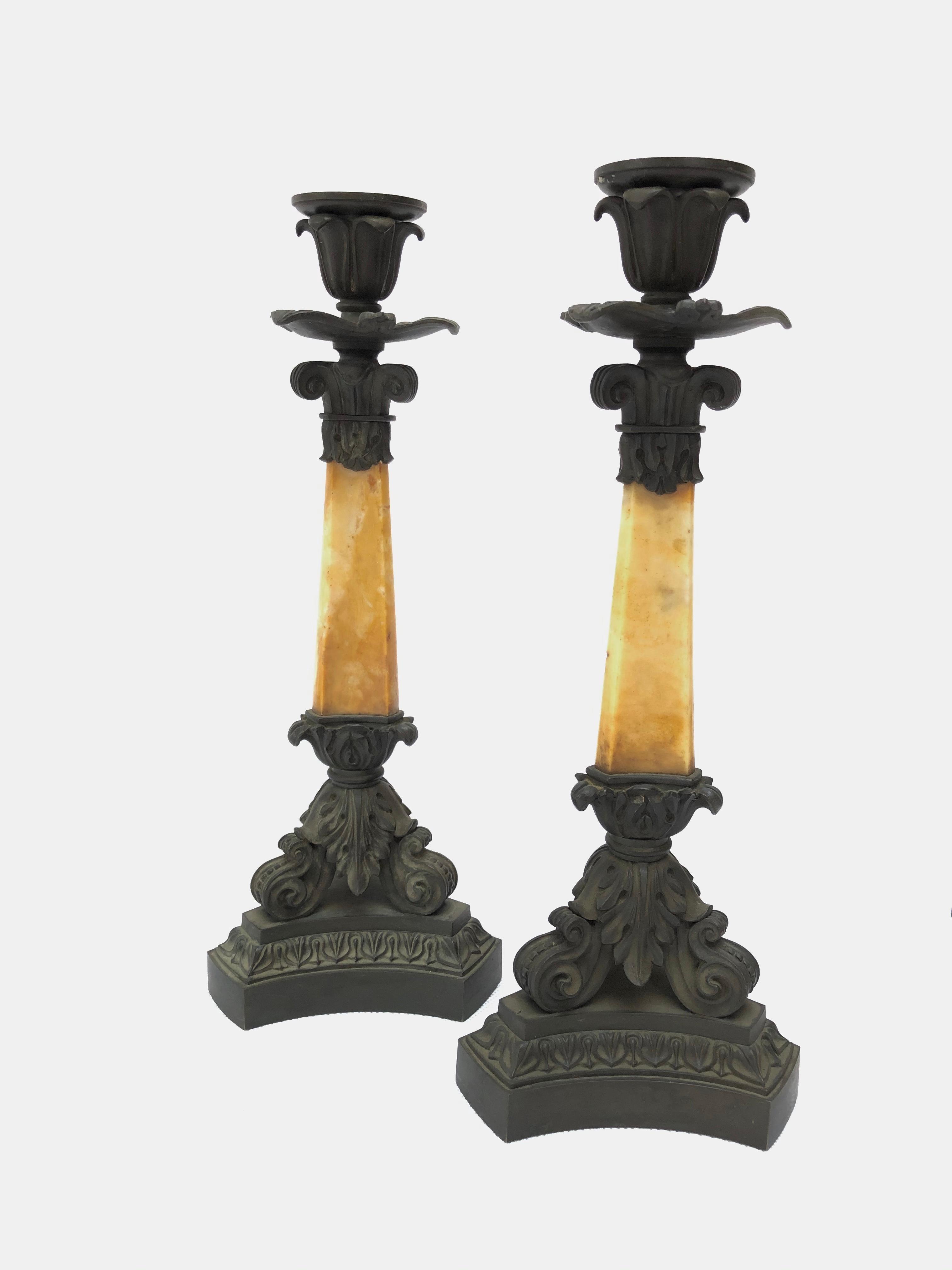 A set of four French mid-19th century patinated bronze and Yellow Sienna marble candlesticks by Deniere, Paris
Each tri-form column surmounted by a candleholder and foliate drip-pan, the base with scrolling mounts centred by an acanthus leaf, the