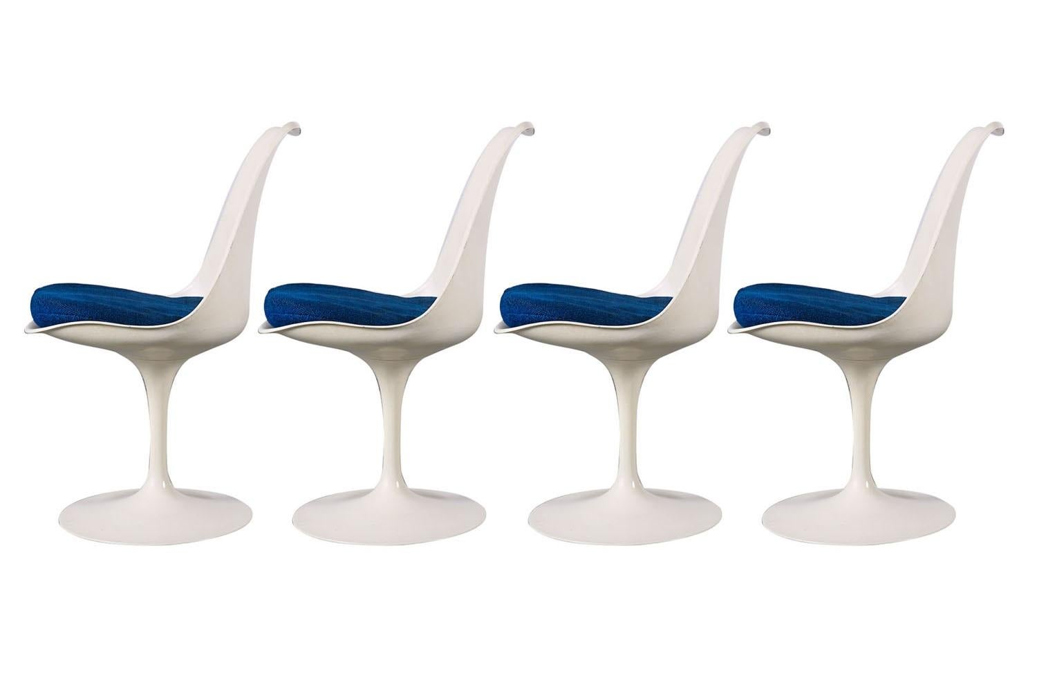 Classic Mid-Century Modern set of four armless tulip, side, dining chairs, for Knoll designed by Eero Saarinen (USA 1910-1961) for Knoll Furniture International in 1956. Features molded white lacquered fiberglass form resting on cast aluminum swivel
