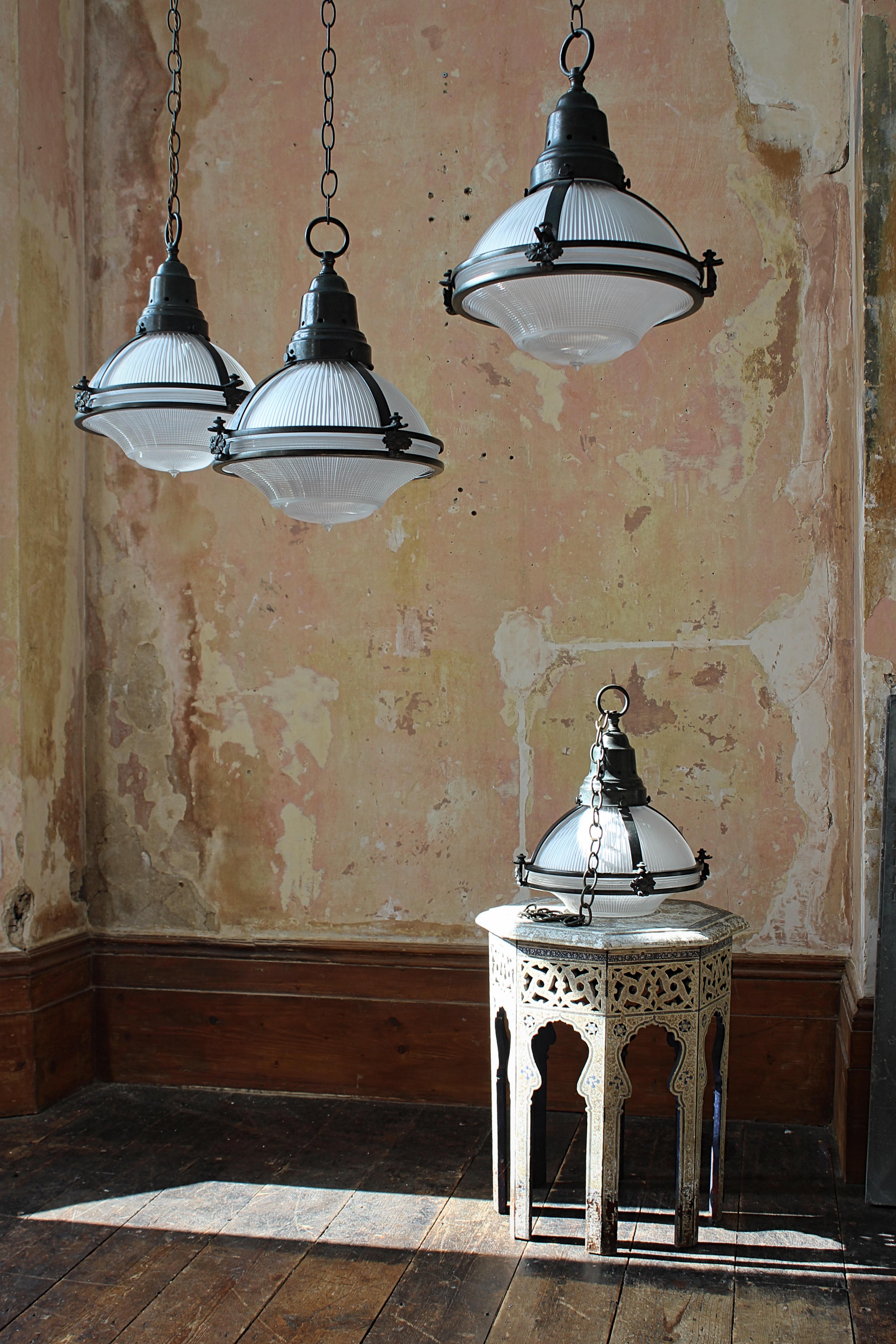 A very good run of four large three part prismatic glass Holophane lanterns, housed within their original elaborate bronze copper cages.

The bronze has a wonderful patina with a sprinkle of verdigris.

All glass sections stamped with the Holophane