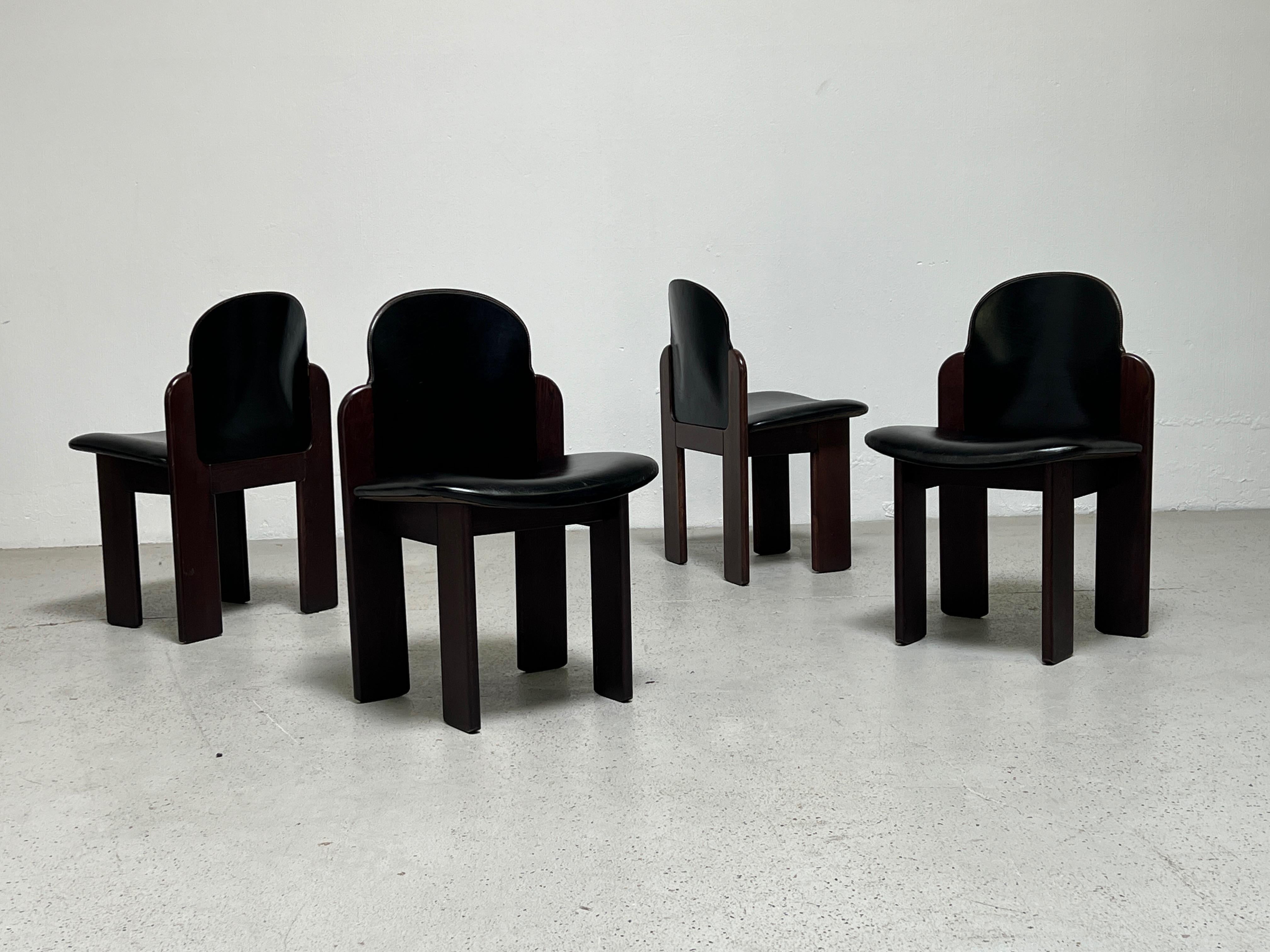 A set of four walnut and black leather chairs designed by Silvio Coppola for Bernini.