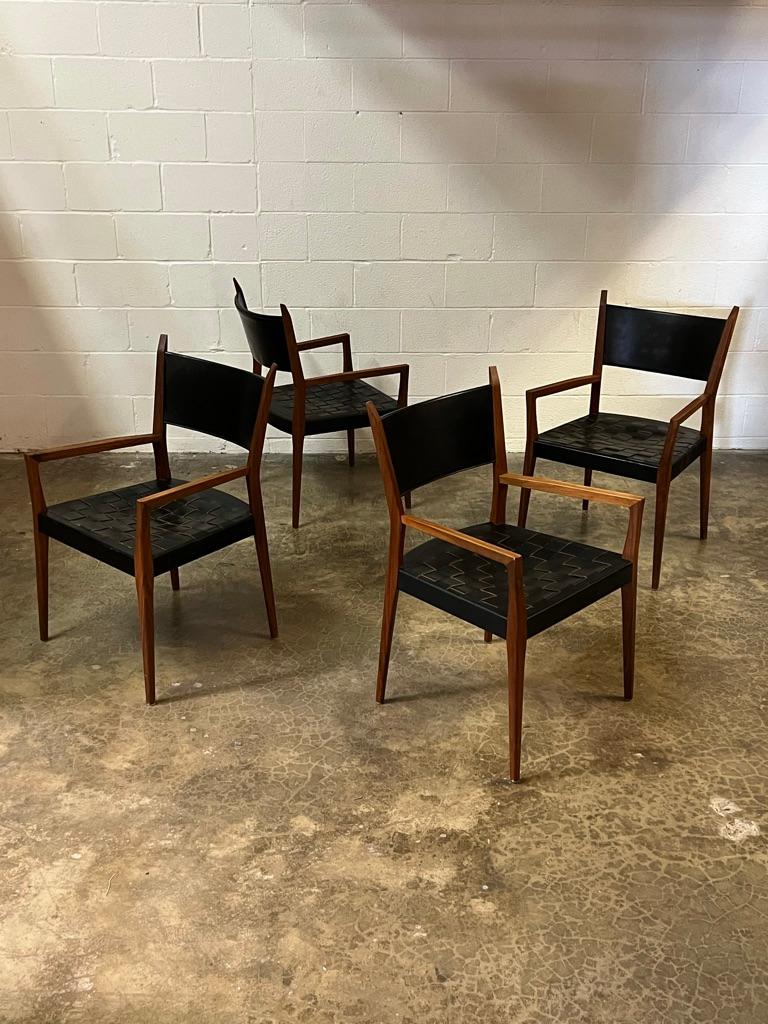 A set of four Paul McCobb walnut armchairs with original woven leather seats.