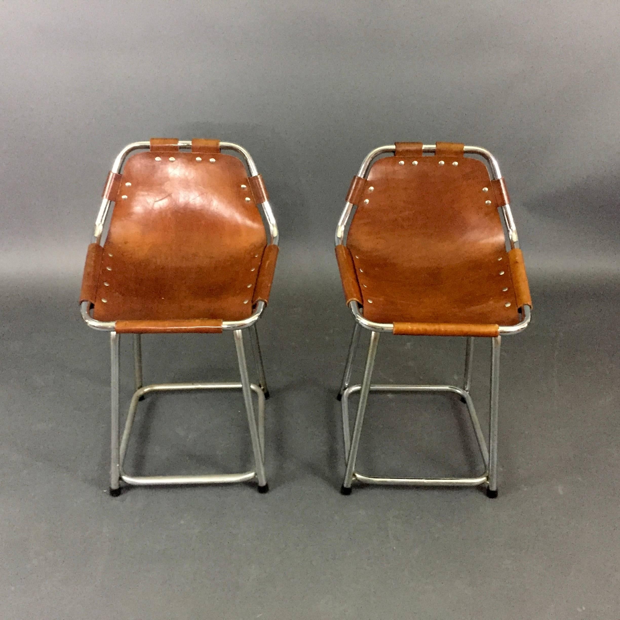 These famous stool in the style of Charlotte Perriand were selected for the ski resorts at Les Arcs in Savoie in the late 1960s, produced by Cassina in Italy. Perfect patina saddle leather is attached to tuber chrome frames with rivets and leather