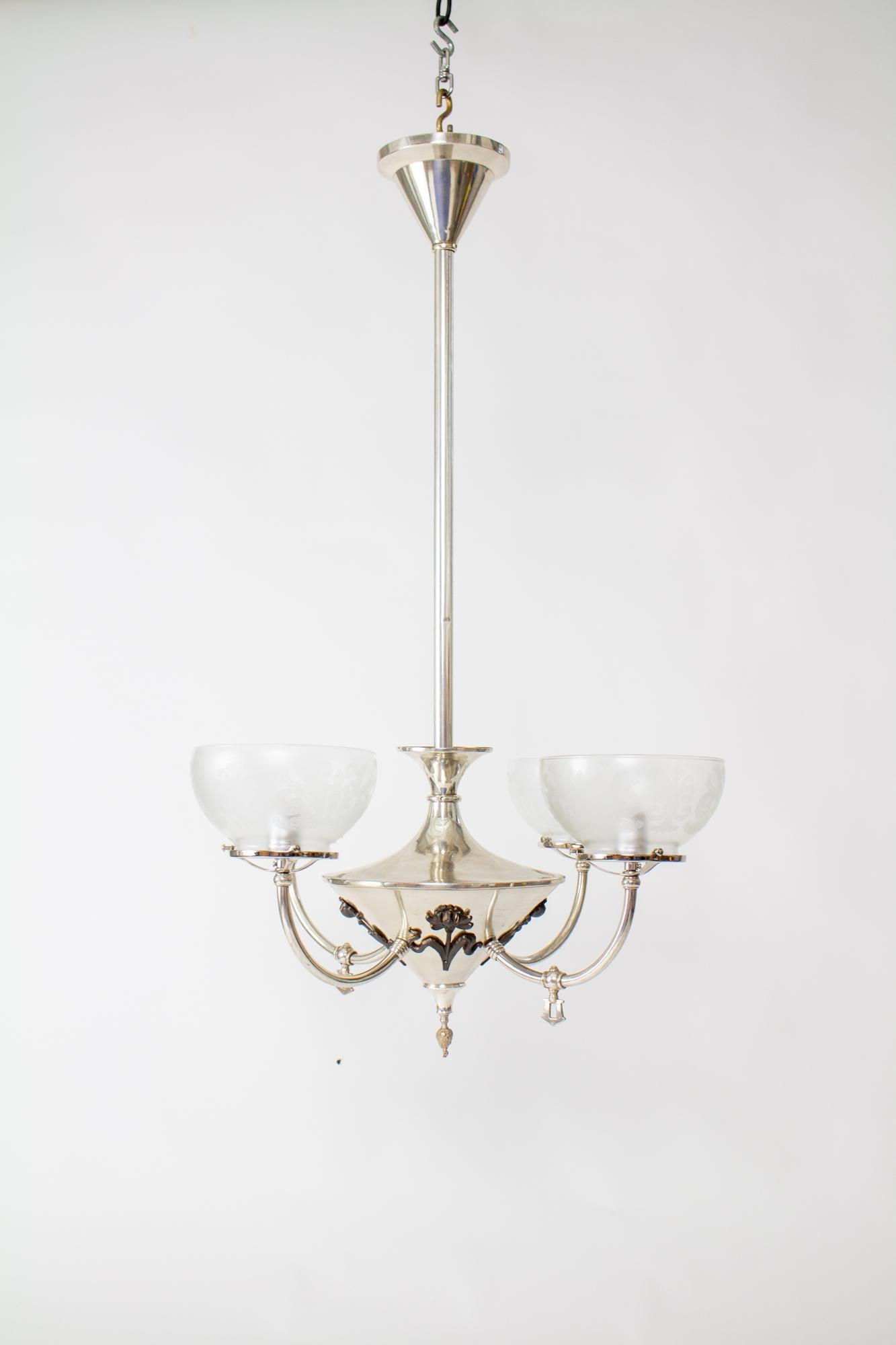 Turn of the century silver art nouveau gas and electric chandelier. Conical shaped canopy and body with four arms curving up. The chandelier is silver plate with flowers on the body in a contrasting dark patina. Two of the arms were originally gas,