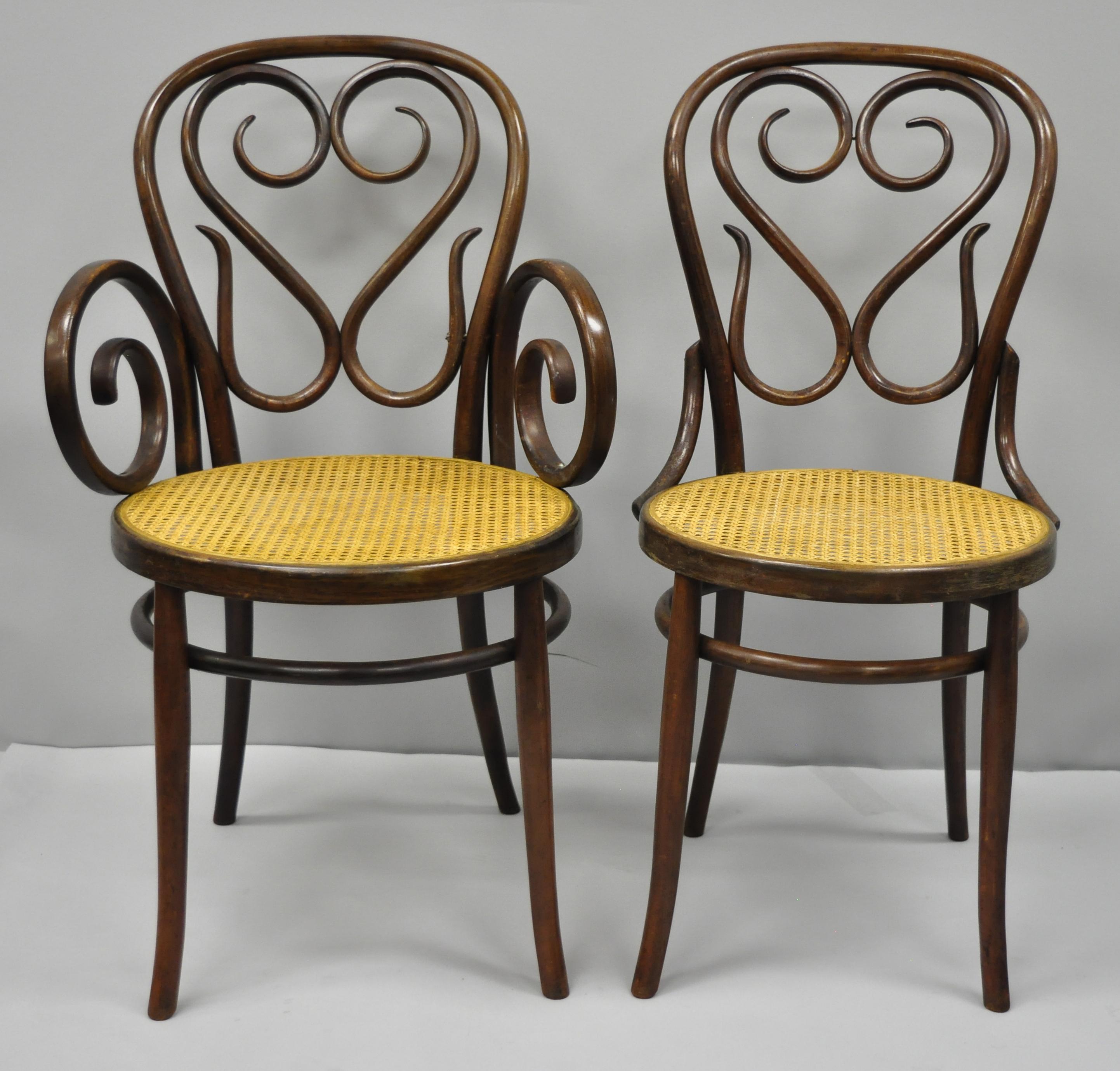 Set of four antique Michael Thonet bentwood round cane seat Bistro dining chairs attributed to Gebruder. Listing includes two armchairs, two side chairs, round cane seats, remnants of label, solid wood construction, beautiful wood grain, great style