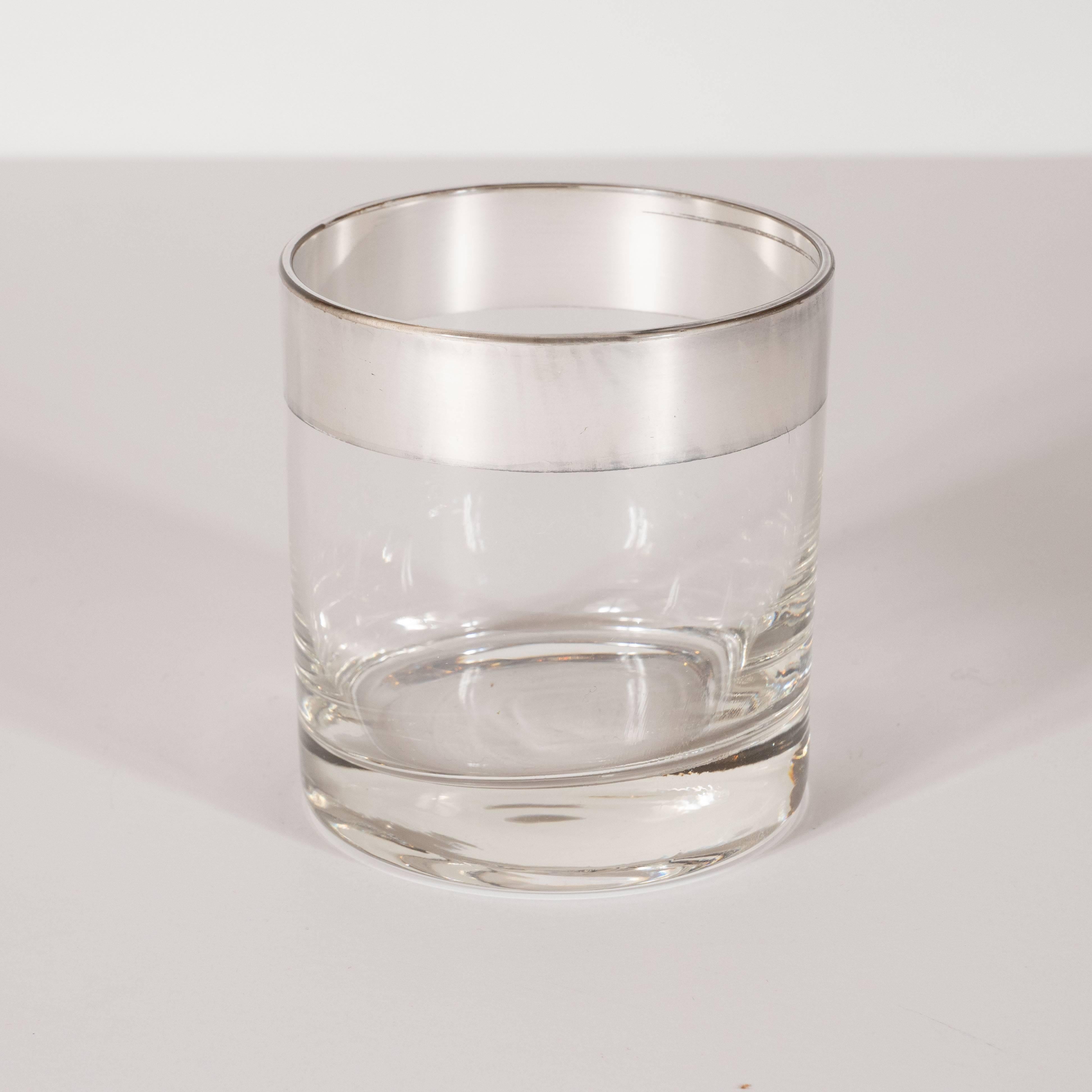This refined set of four lowball glasses were designed in California by the esteemed Mid-Century Modern designer Dorothy Thorpe, circa 1950. Composed of simple cylindrical forms, they offer band detailing in sterling silver overlay at the top of