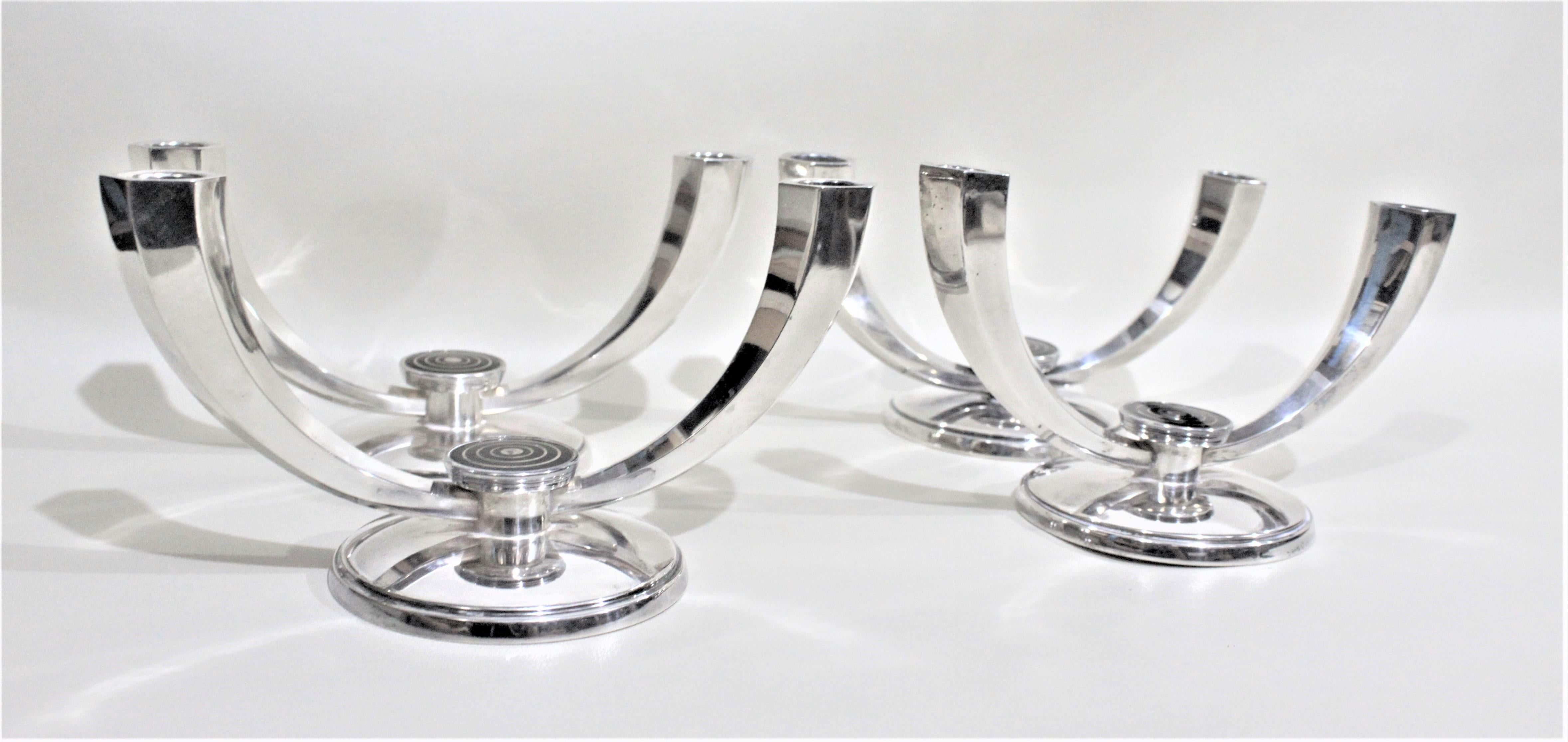 This set of four double branch sterling candlesticks were made in the period and style of Mid-Century Modern and are signed by J. Tostrup of Norway. Each candlestick has a black enameled 'bulls eye' style medallion between the two branches. The