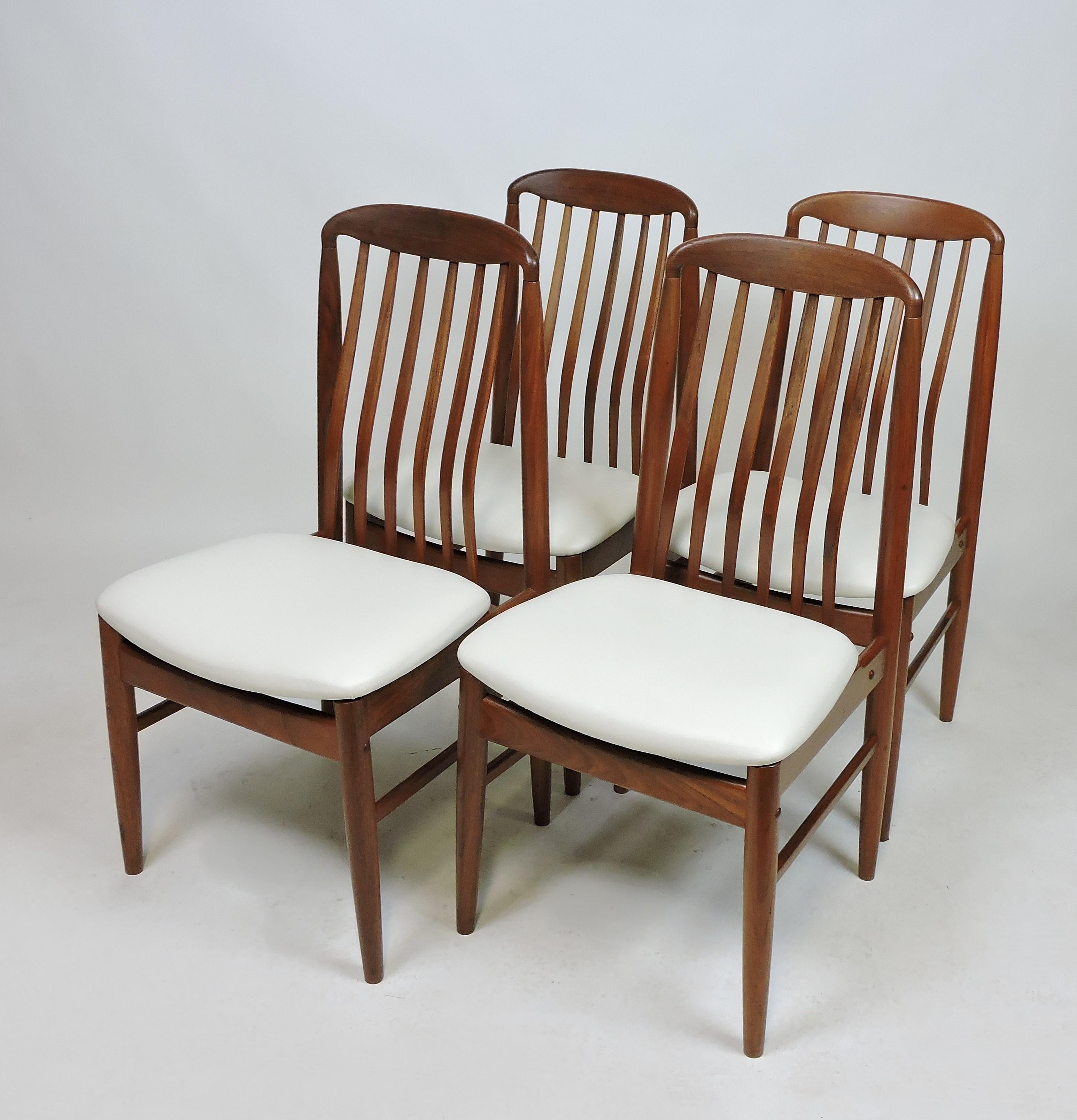 Set of four BL10 Sanne dining chairs designed by Danish designer Benny Linden. These chairs are made of solid teak with contoured spindle backs and seats newly upholstered in a white Naugahyde. Very comfortable chairs with a graceful look.