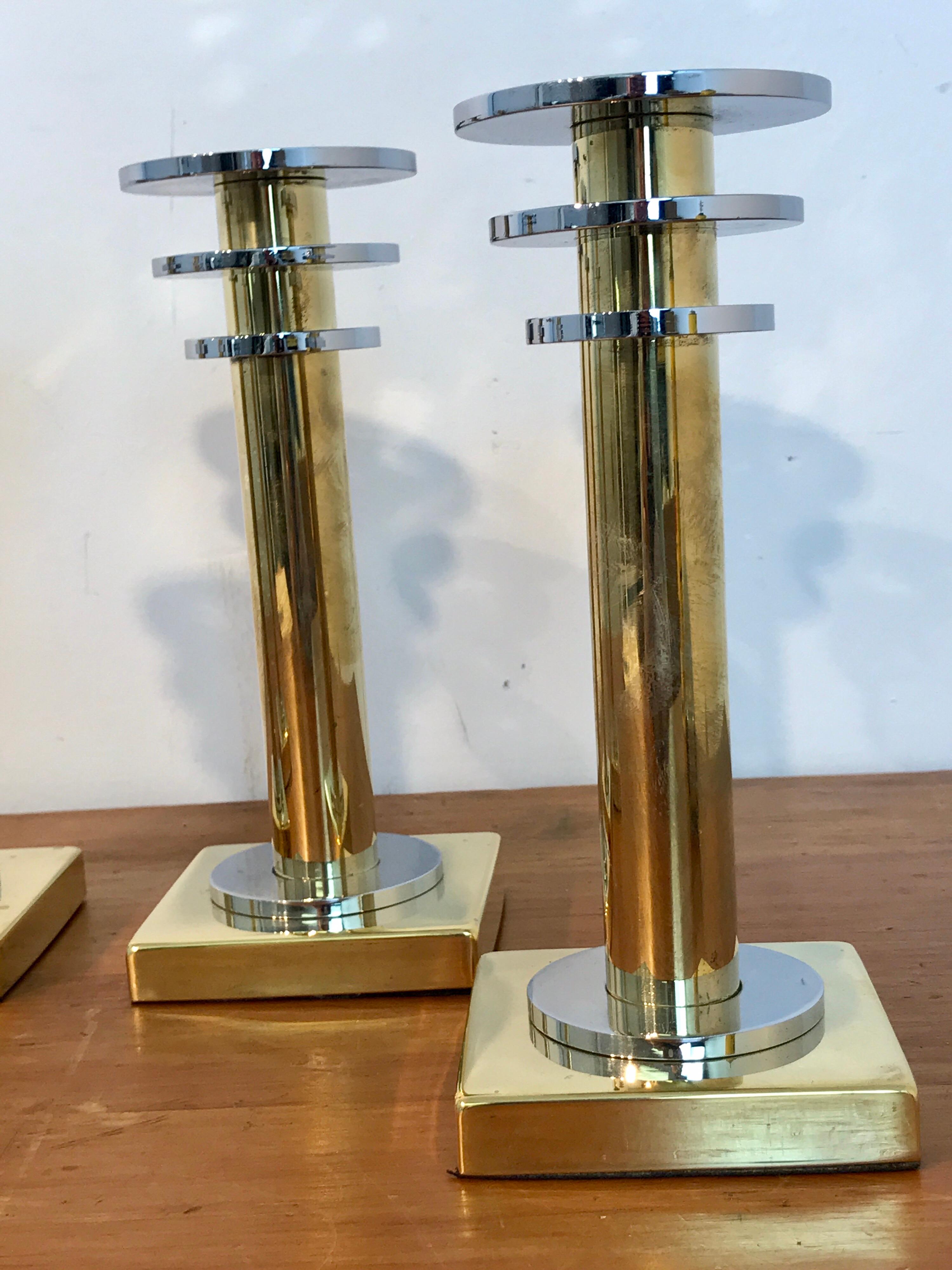Four modern brass and silver plate candlesticks in the style Swid Powell, each one with three silver plated ring top on a brass pedestal base.