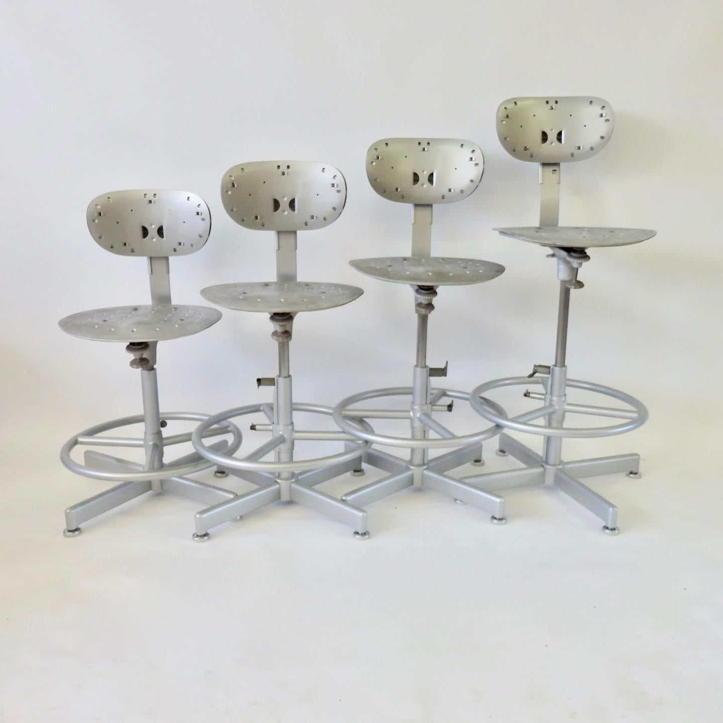 Industrial bar stools with five way adjustments. Seat height - depth of backrest - height of backrest - spring tension at front edge of seat - footrest height. Powder coated steel base, polished steel upright shaft, aluminum seat pad. New glides
