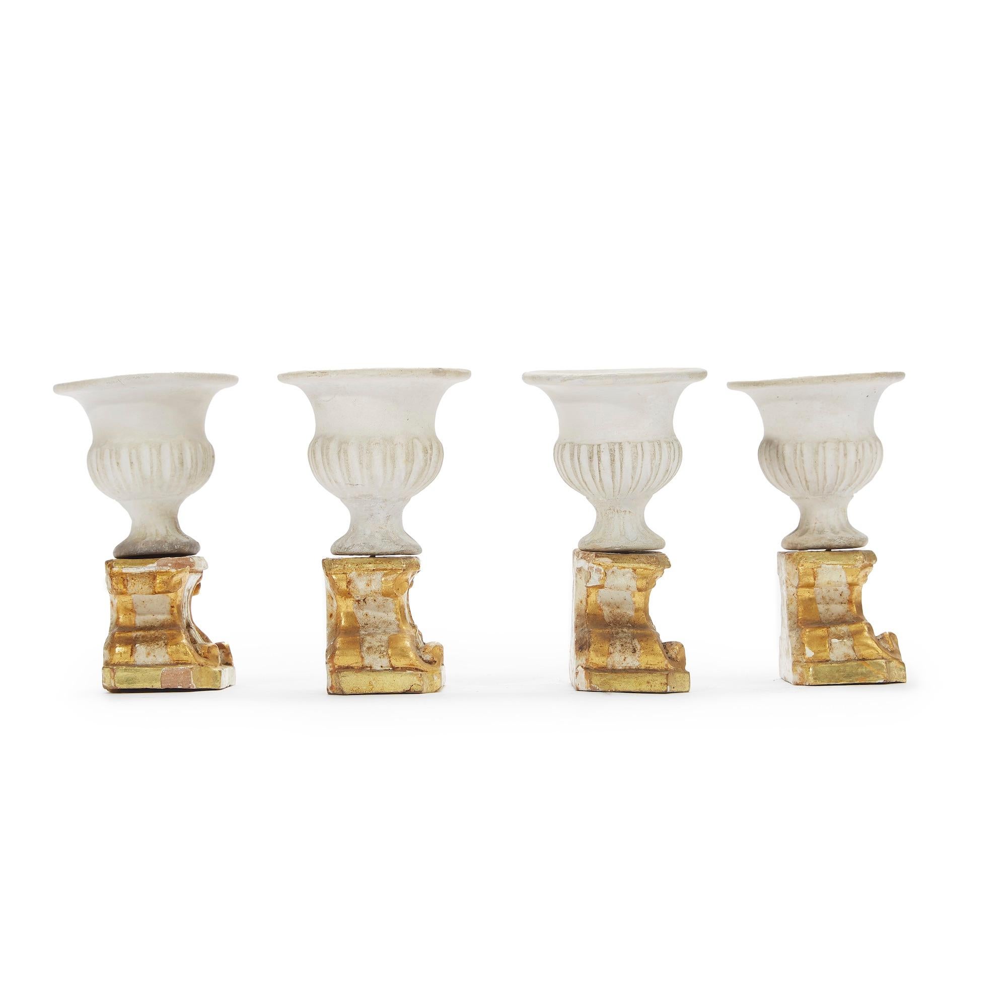 Quattro Decorazioni da Tavola Neoclassiche composte da quattro basamenti in legno intagliato, laccato e dorato sormontati da un vaso mediceo in biscuit sovrastante. 
Di origine Italiana, risalgono alla fine 1700 e si presentano in buono stato di