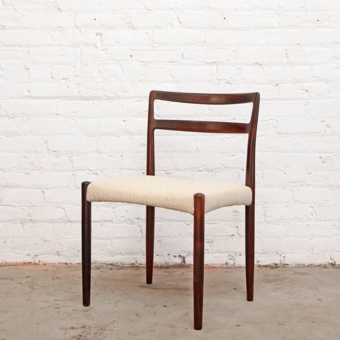 Set of four sculpted rosewood dining chairs by Niels Moller. Recently reupholstered in off white wool boucle.