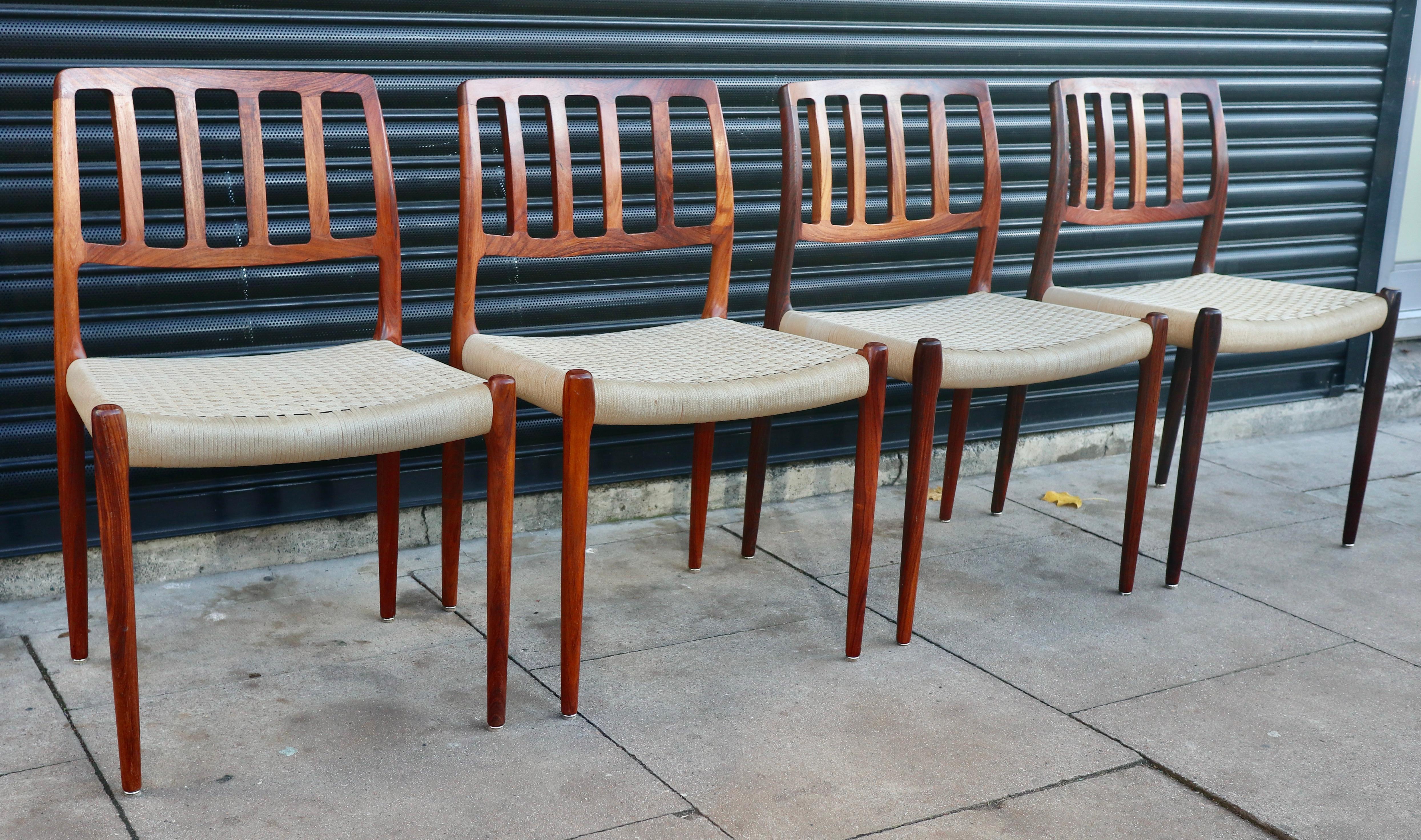 Four vintage rosewood framed Danish model 83 dining chairs with woven seats. Designed by Niels O Moller and manufactured by J.L. Møller.  Although,  these chairs are in very good vintage condition, having been restored, refurbished, cleaned and