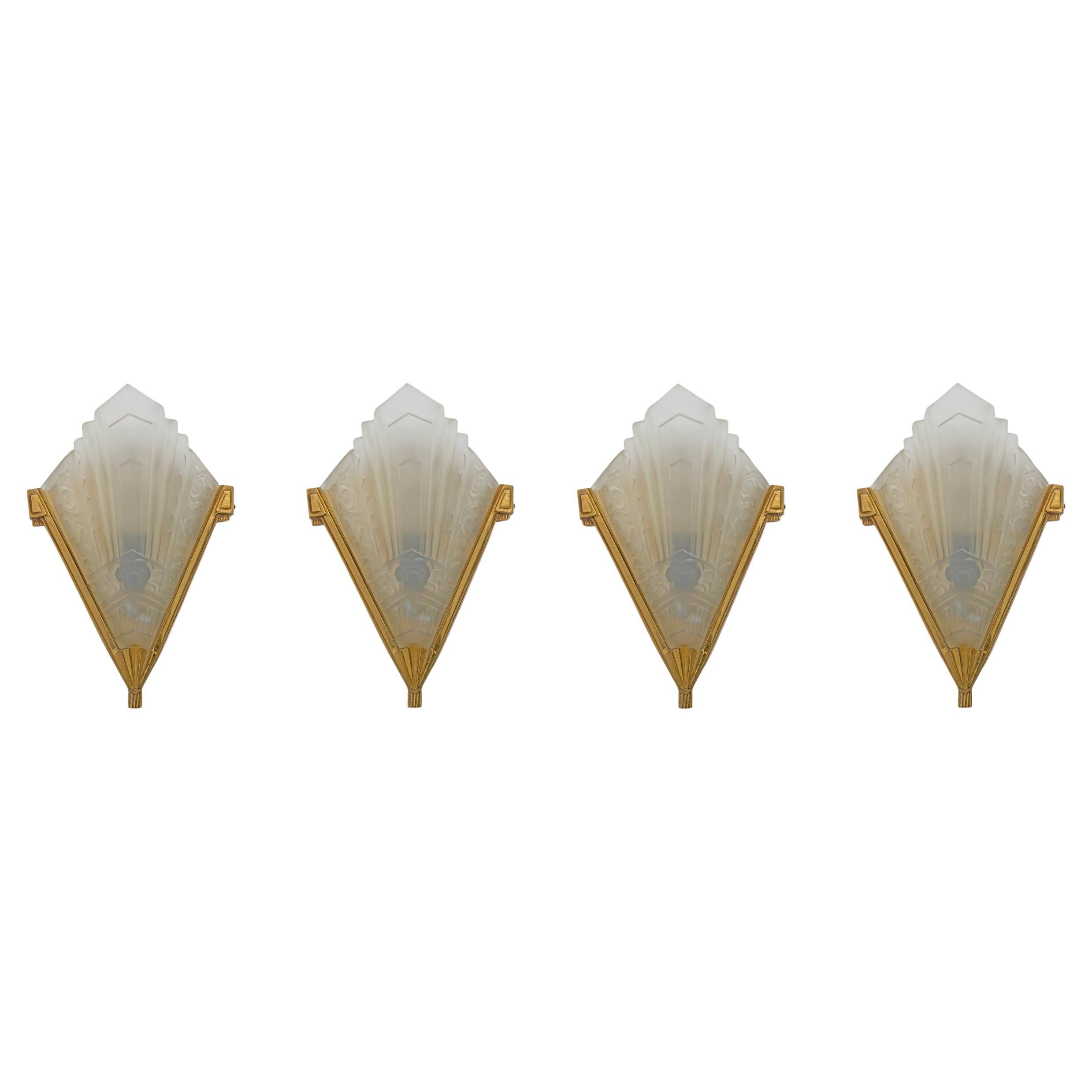 Four Art Deco wall lamps, France, c. 1930, lampshades in clear glass pressed into a mold and etched, the glasses have geometric and floral motifs, brass structure. The lamps have been rewired to US and European standards with lamp holders with